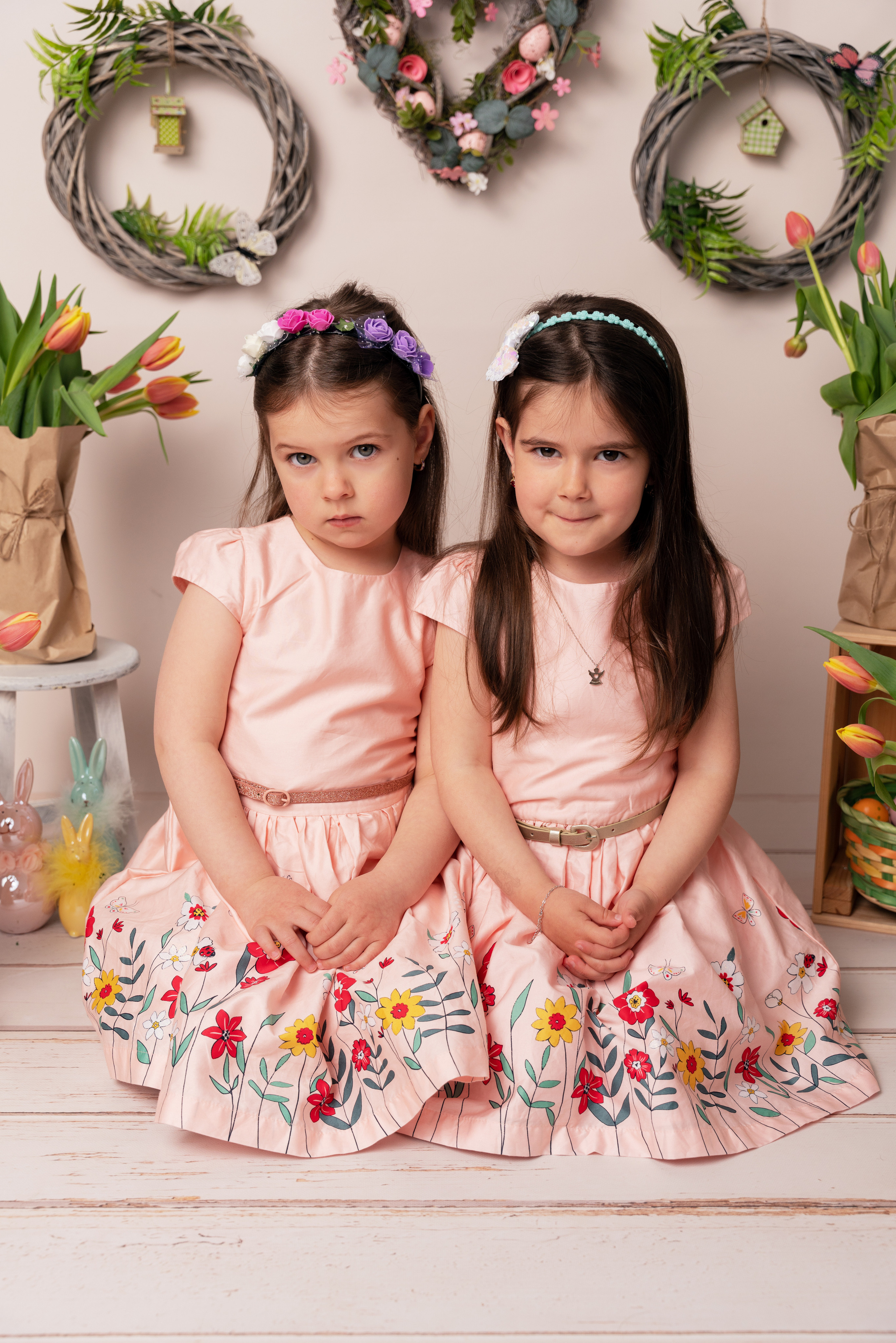 zwei schwestern in kränzen und rosa kleidern feiern ostern
