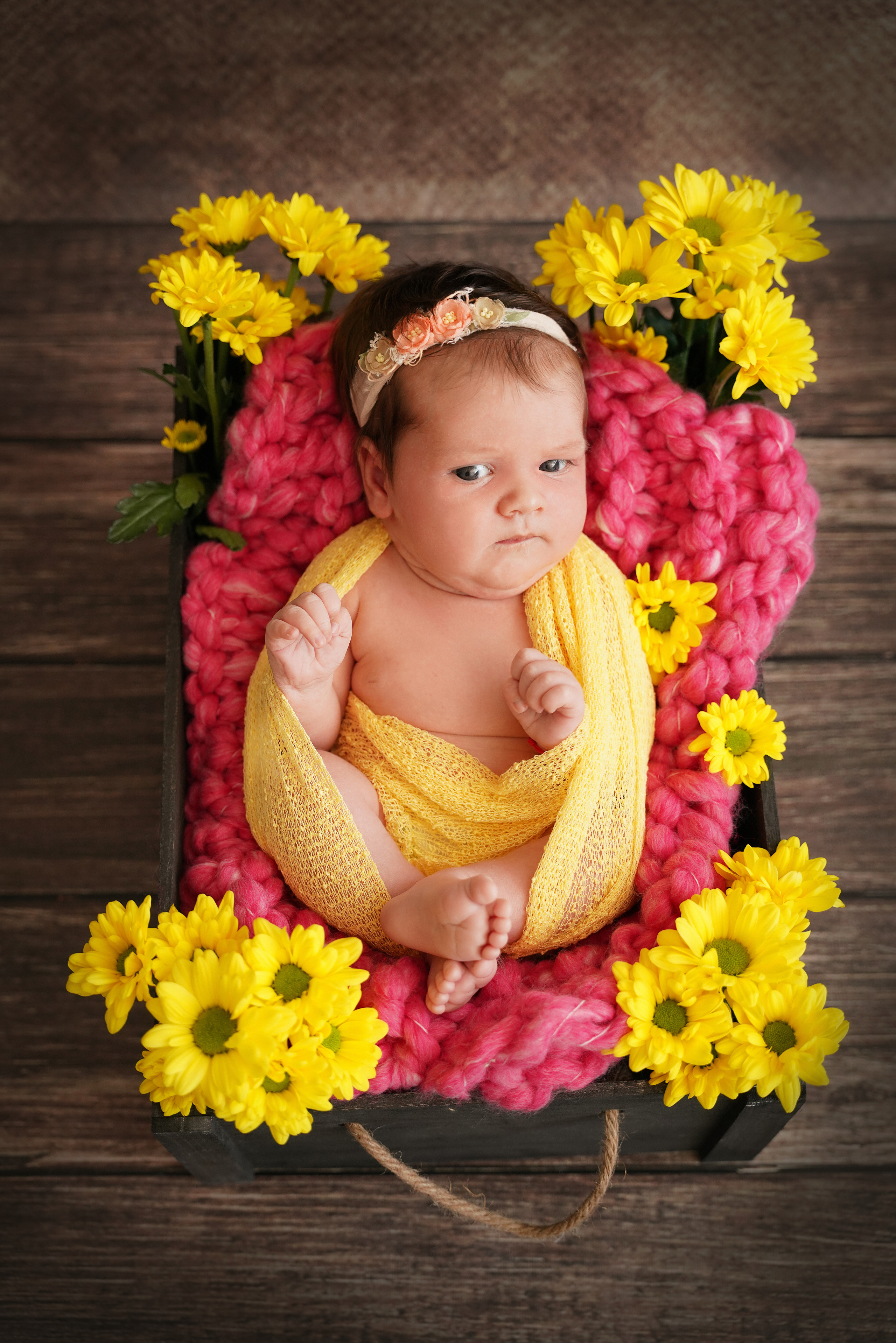 das Baby liegt auf dem Rücken, umgeben von gelben Gartensitzen