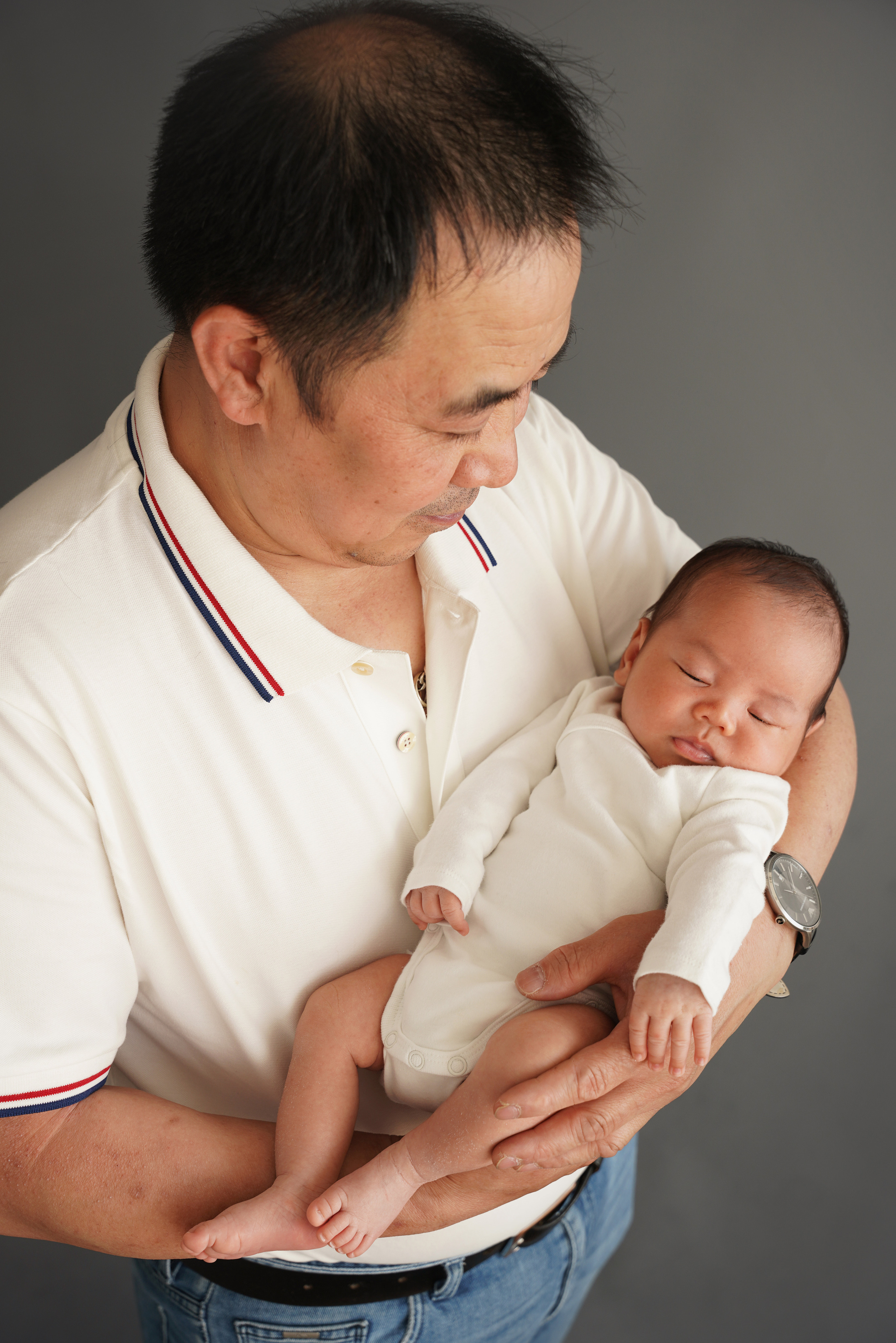 auf dem Foto schaut der Vater liebevoll auf seinen Sohn, der in seinen Armen liegt