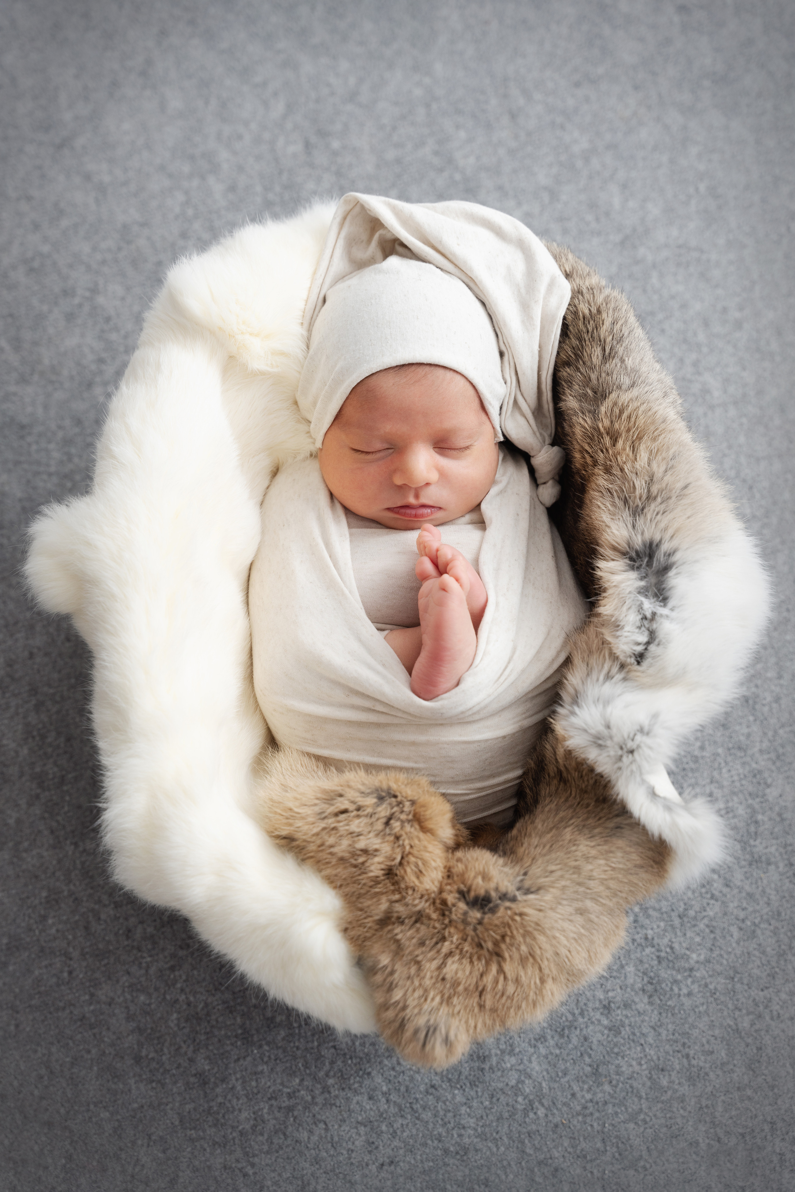 Beim Fotoshooting schläft ein gewickeltes Baby ruhig in einem Korb