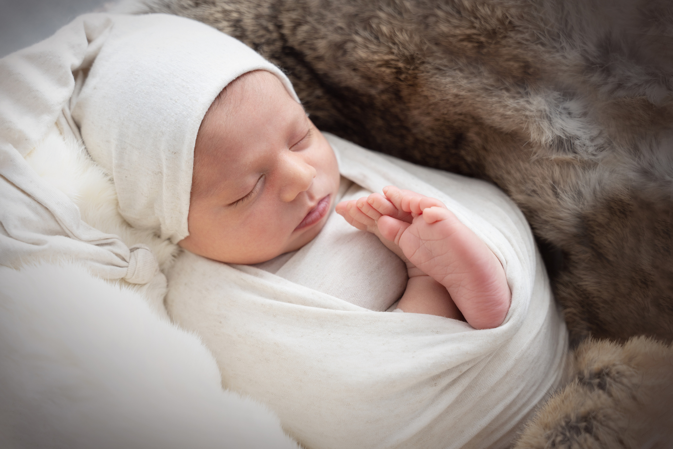 Baby in einem Milchanzug schläft zusammengerollt