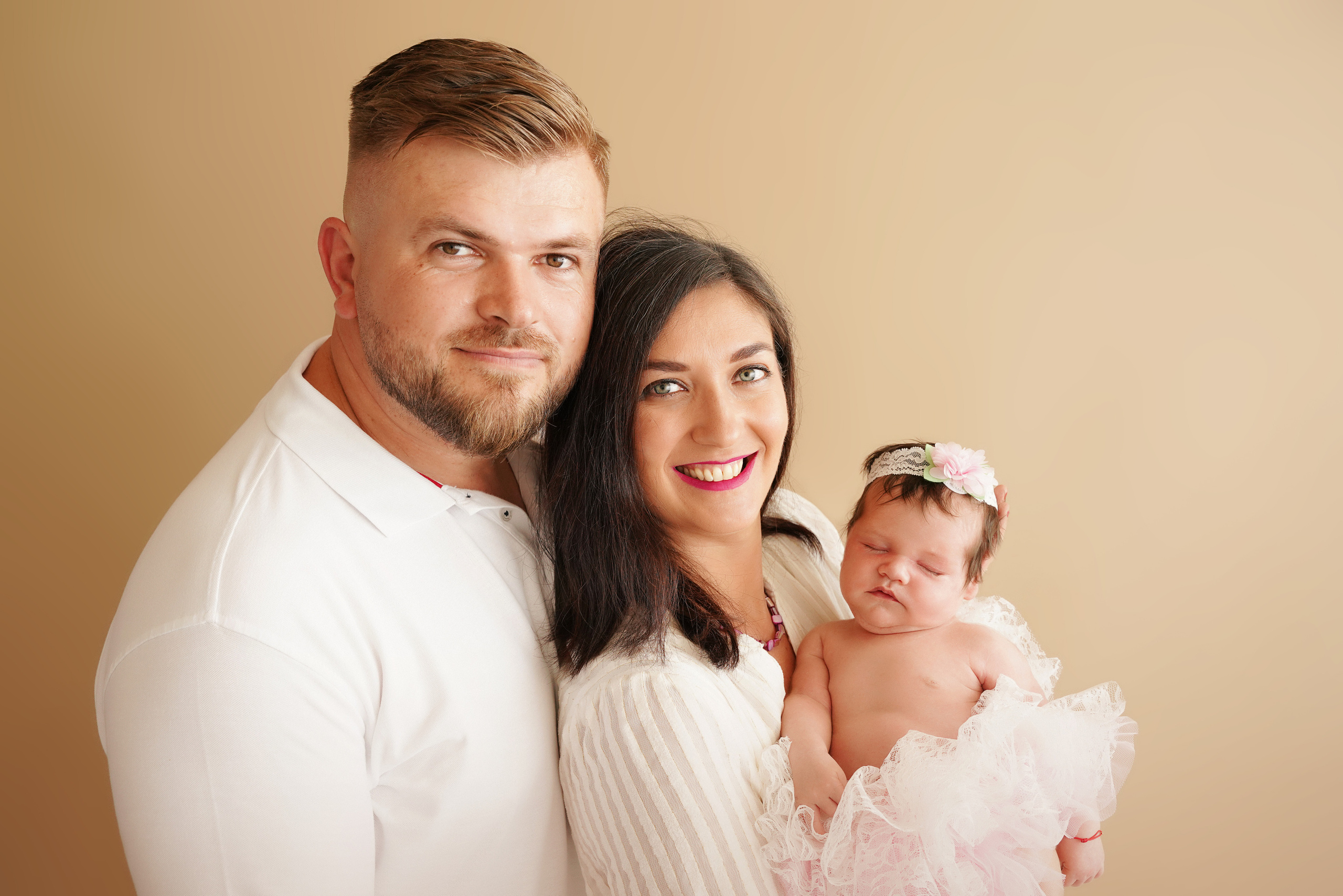 eine Familie in weißen Hemden und ein Neugeborenes in einem üppigen Kleid