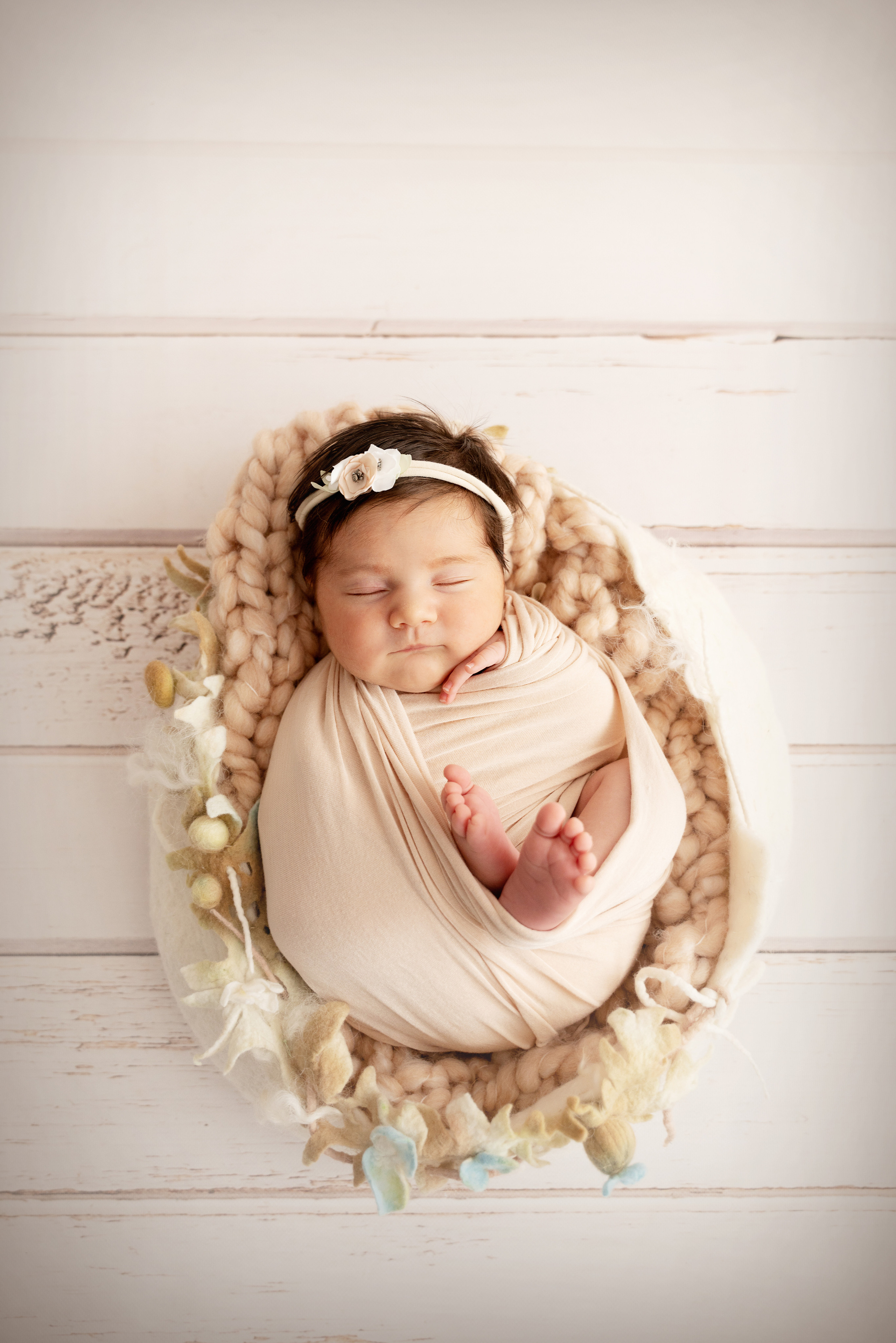 Studiofoto eines gewickelten neugeborenen Mädchens in einem Nest