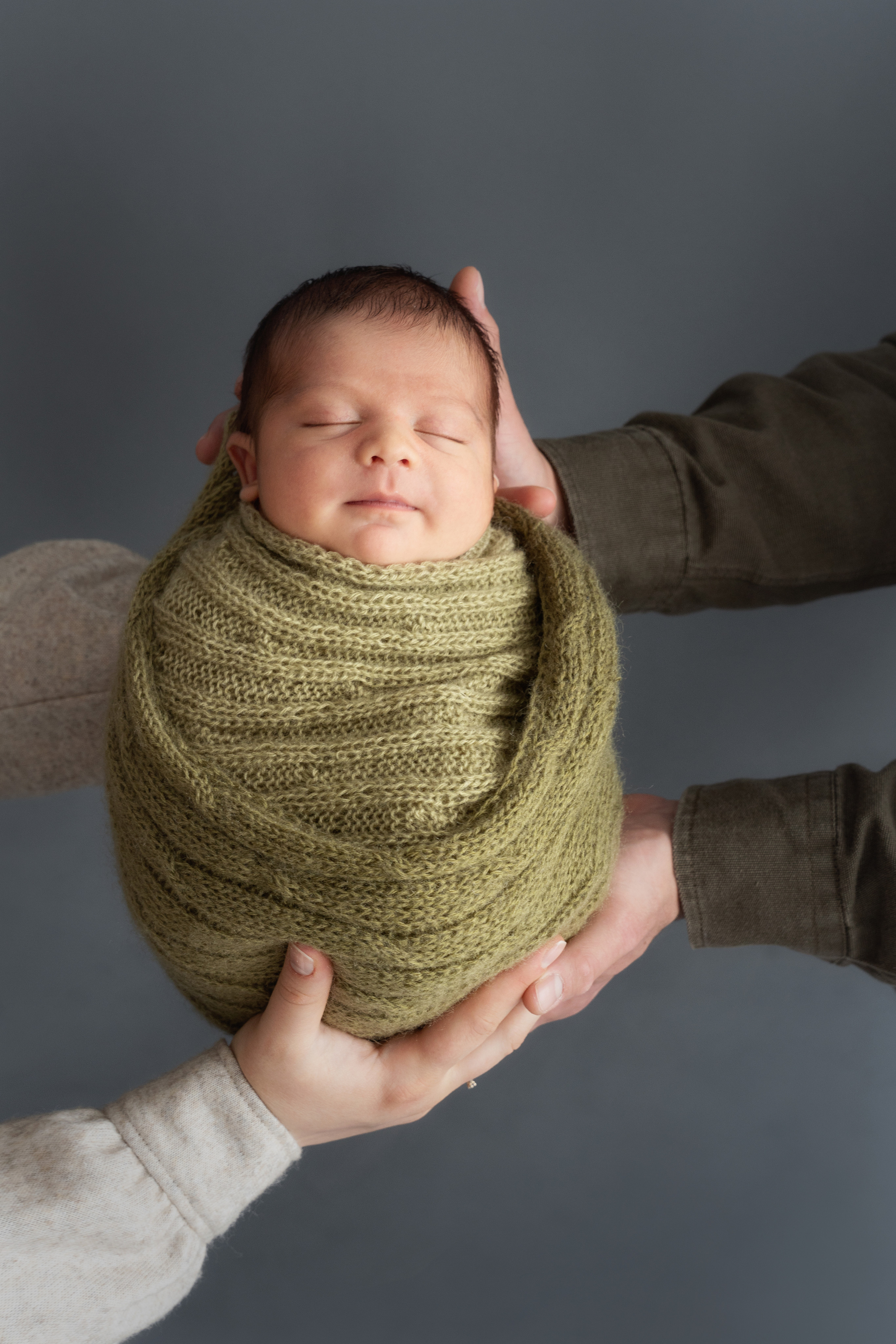 Auf diesem Foto schläft das Baby friedlich in den Armen seiner Eltern.