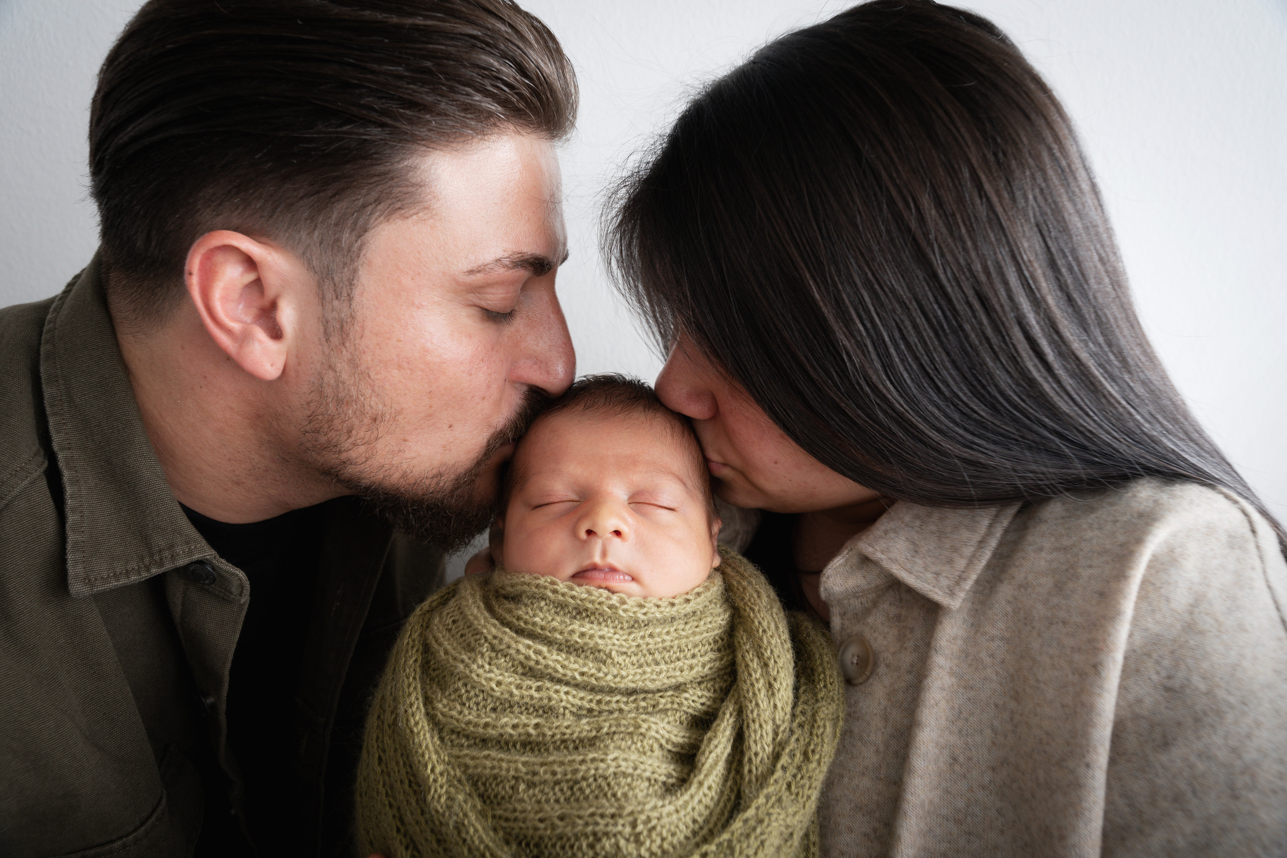 Auf diesem Familienfoto befindet sich ein Neugeborenes zwischen seinen Eltern