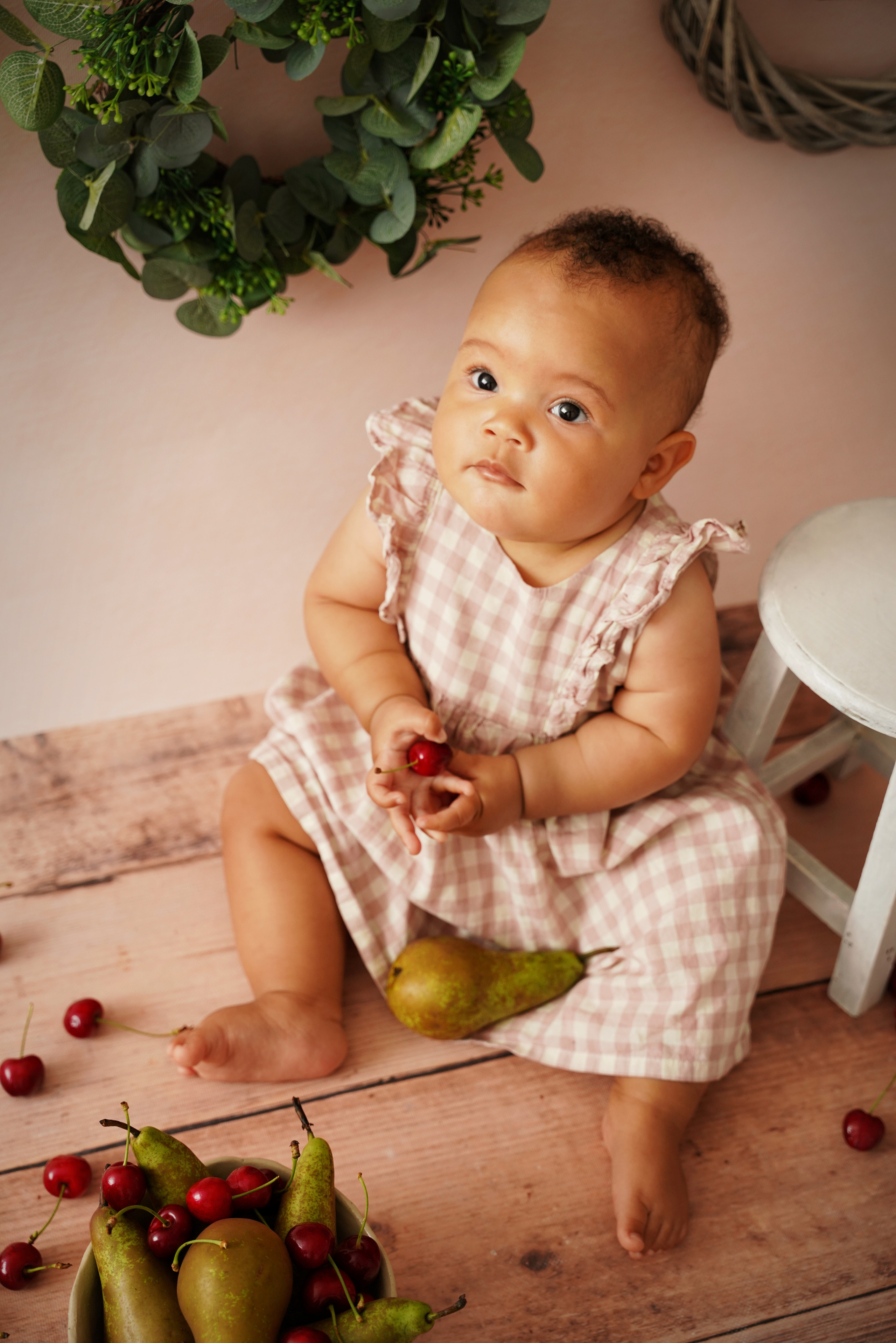Fotosession eines einjährigen Mädchens mit Birnen und Kirschen