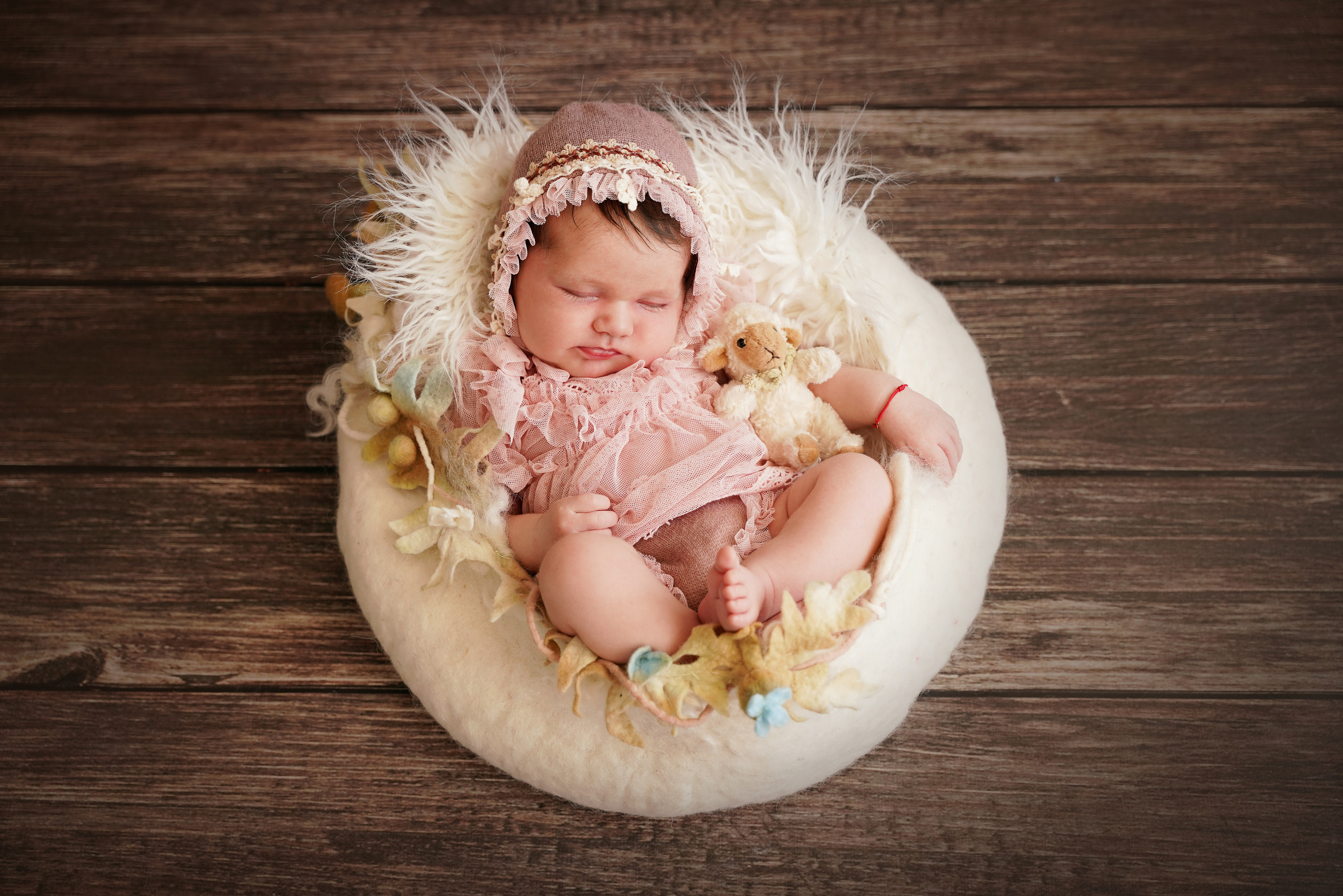 Neugeborenes auf einer flauschigen weißen Matte in einem rosa Anzug