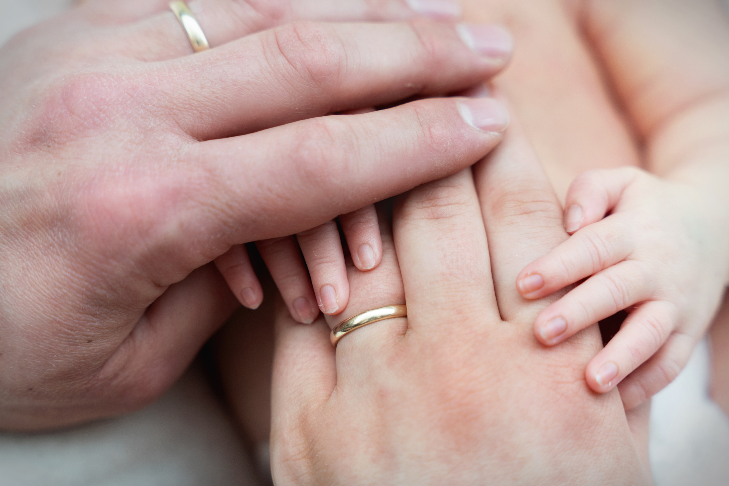 auf dem bild die hände von mama, papa und baby