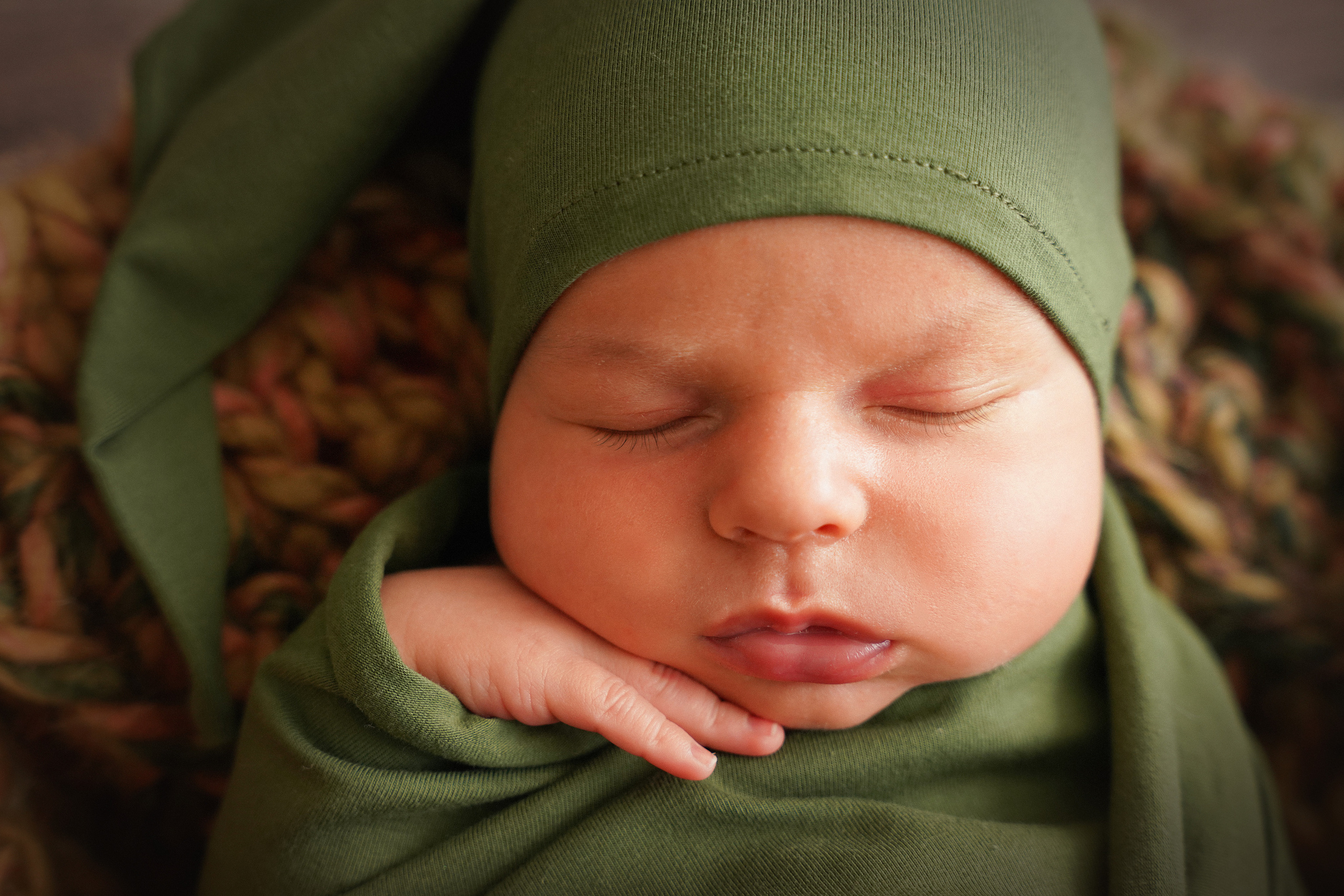 Porträt eines neugeborenen Babys mit einem Griff unter dem Kinn