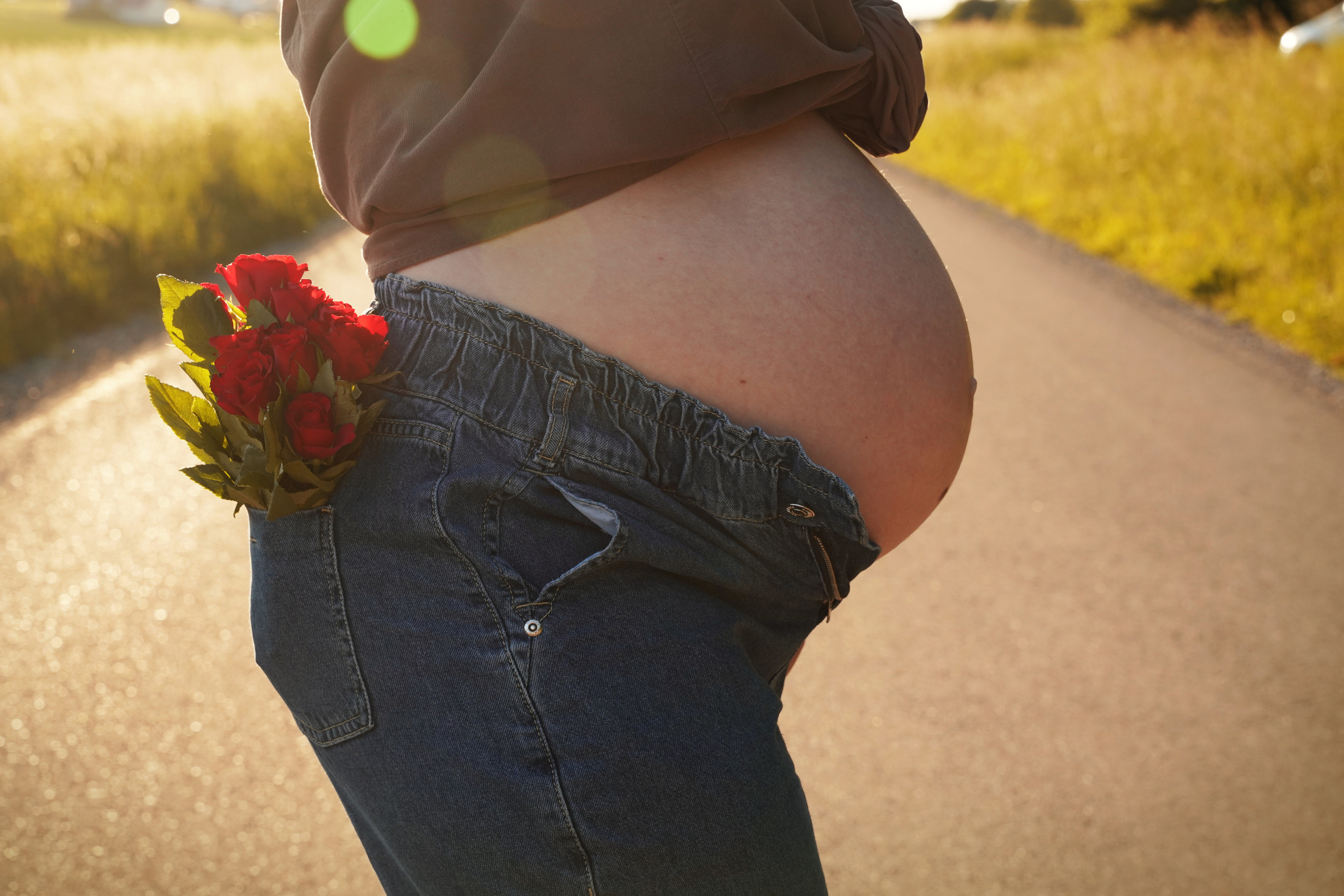 Kreatives Fotoshooting der Schwangerschaft mit Blumen in der Gesäßtasche