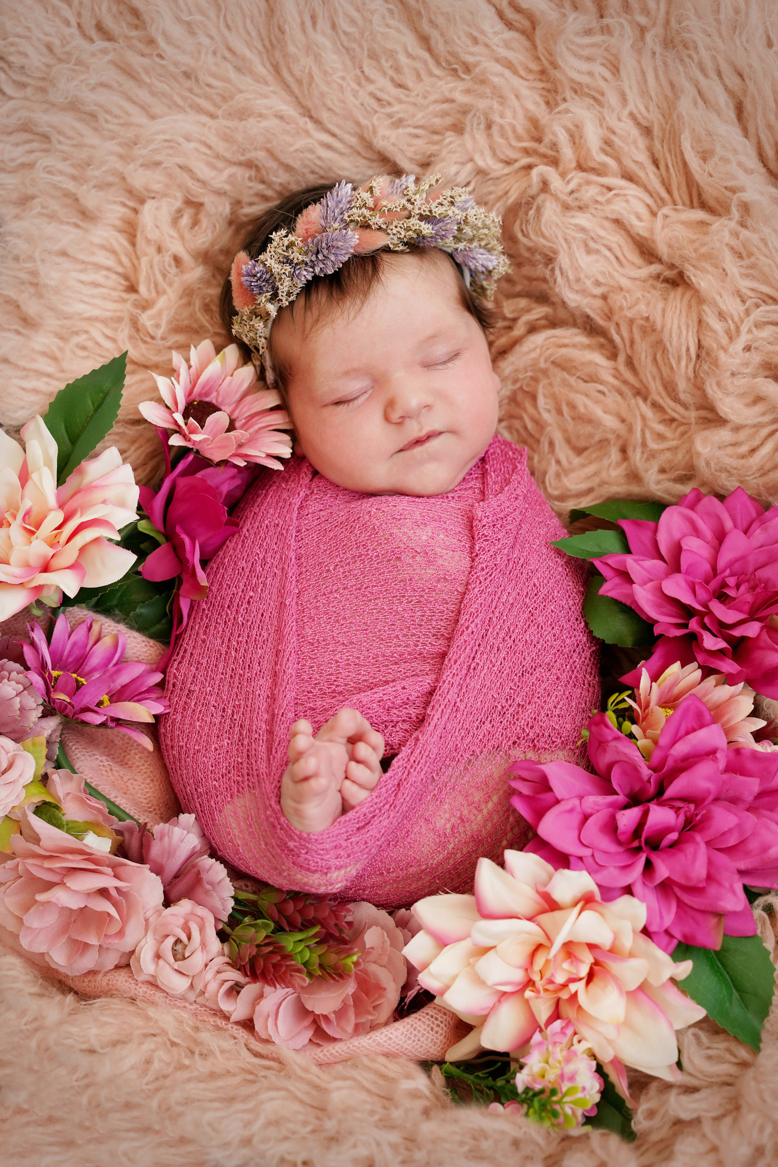 neugeborenes Mädchen liegt auf einem rosa Flocatty mit Blumen