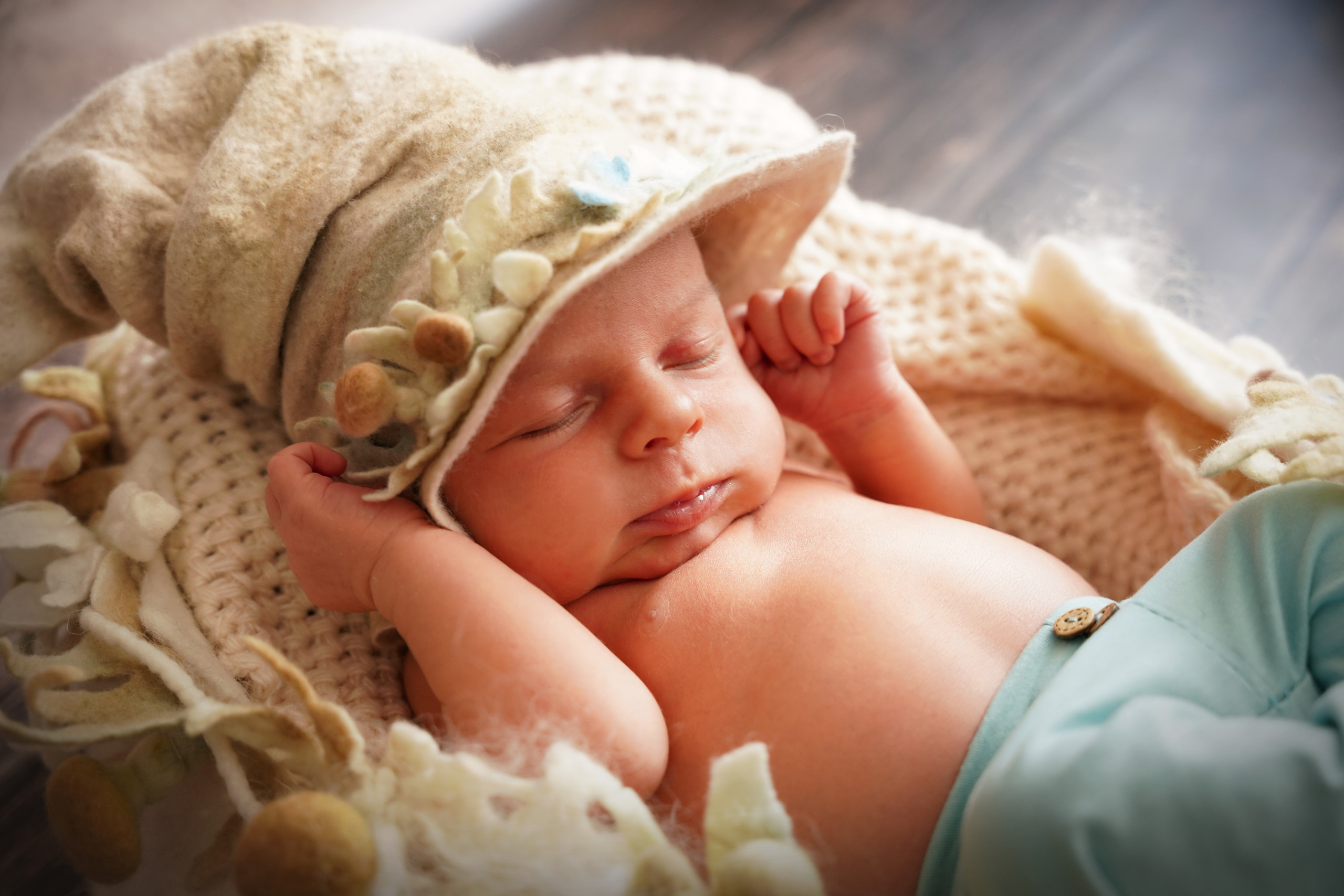 Auf dem Foto hält das Baby seinen Hut mit kleinen Händen