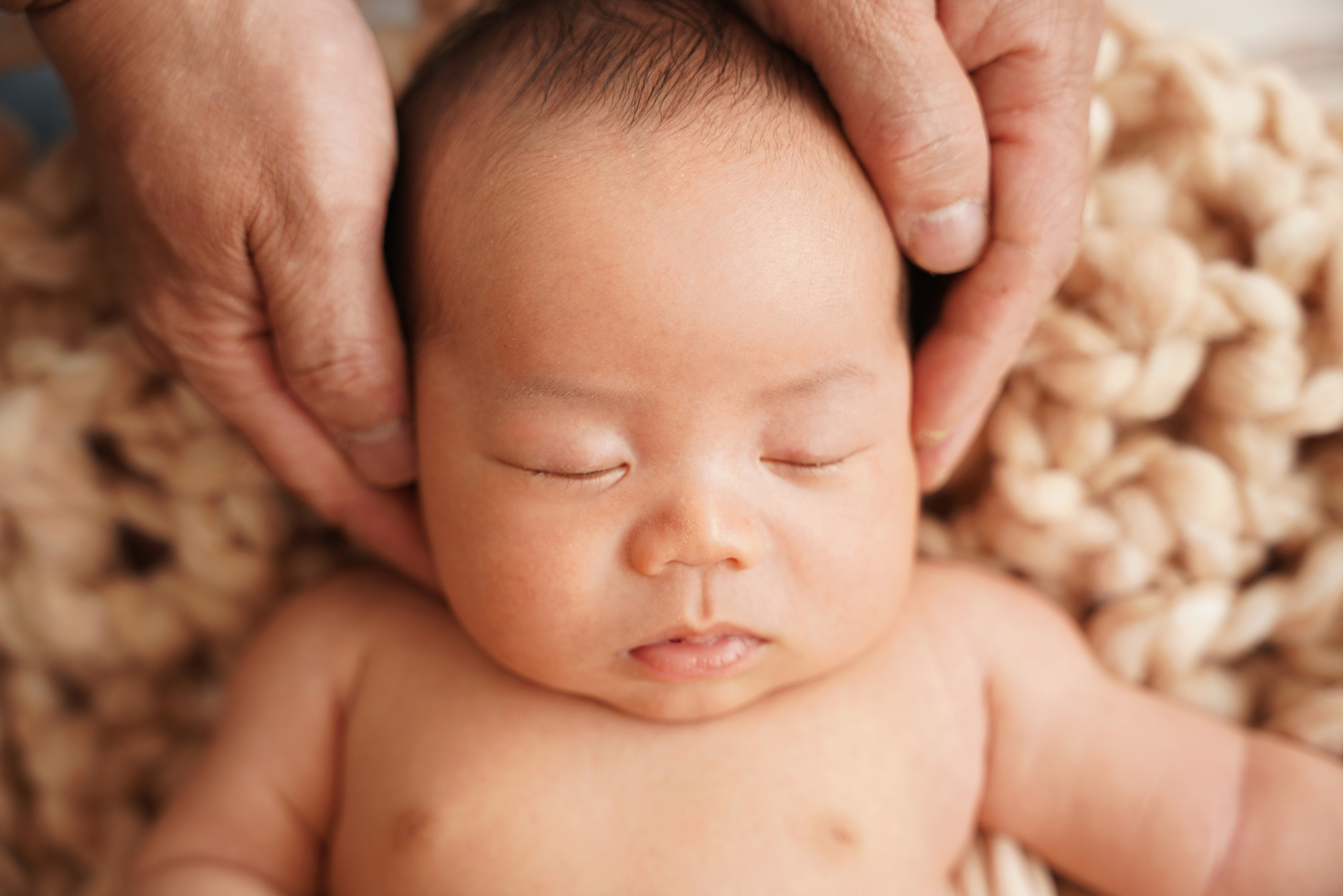 der Kopf des Neugeborenen wird von den Händen der Mutter bedeckt