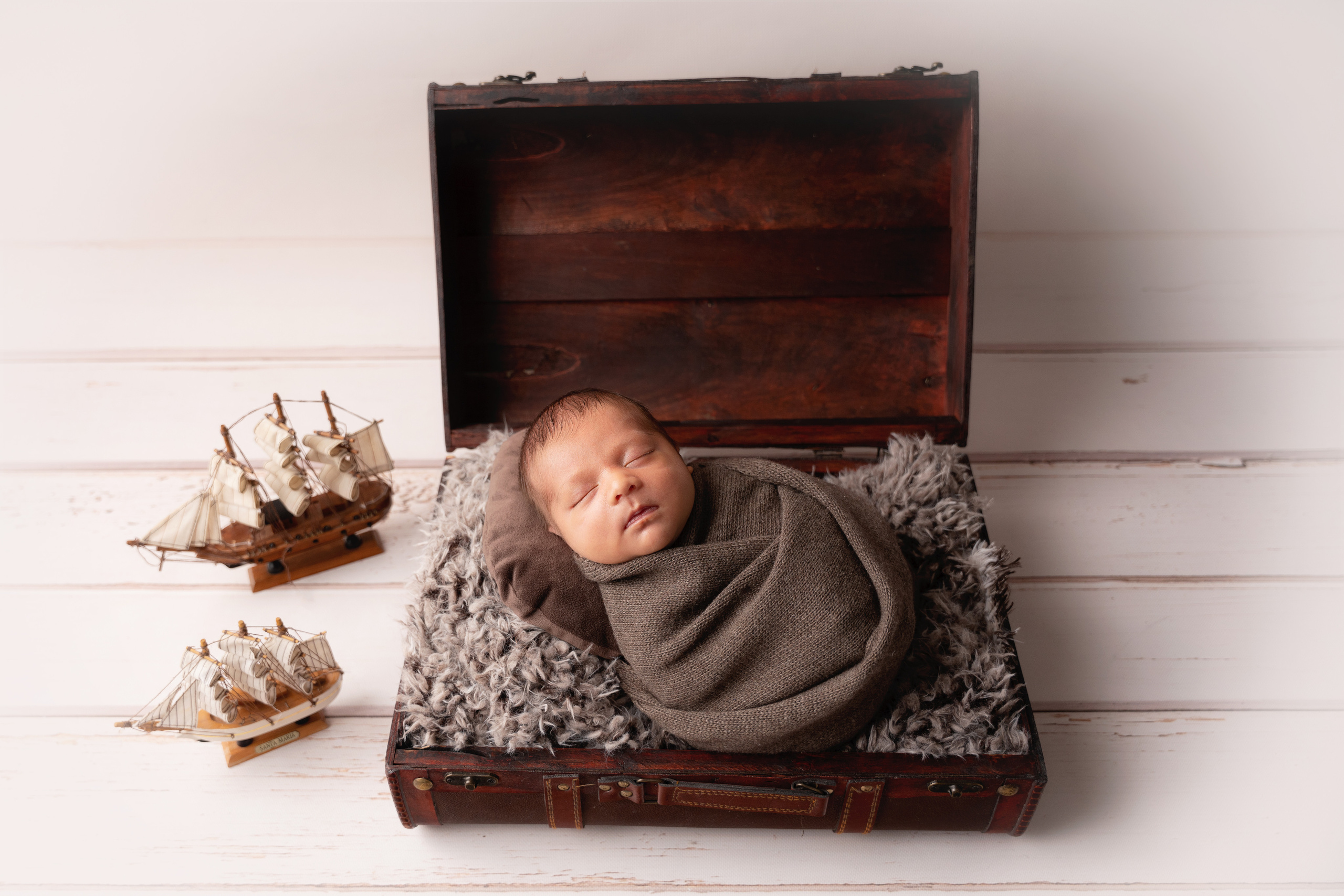 Studiofoto eines Babys auf einem Koffer