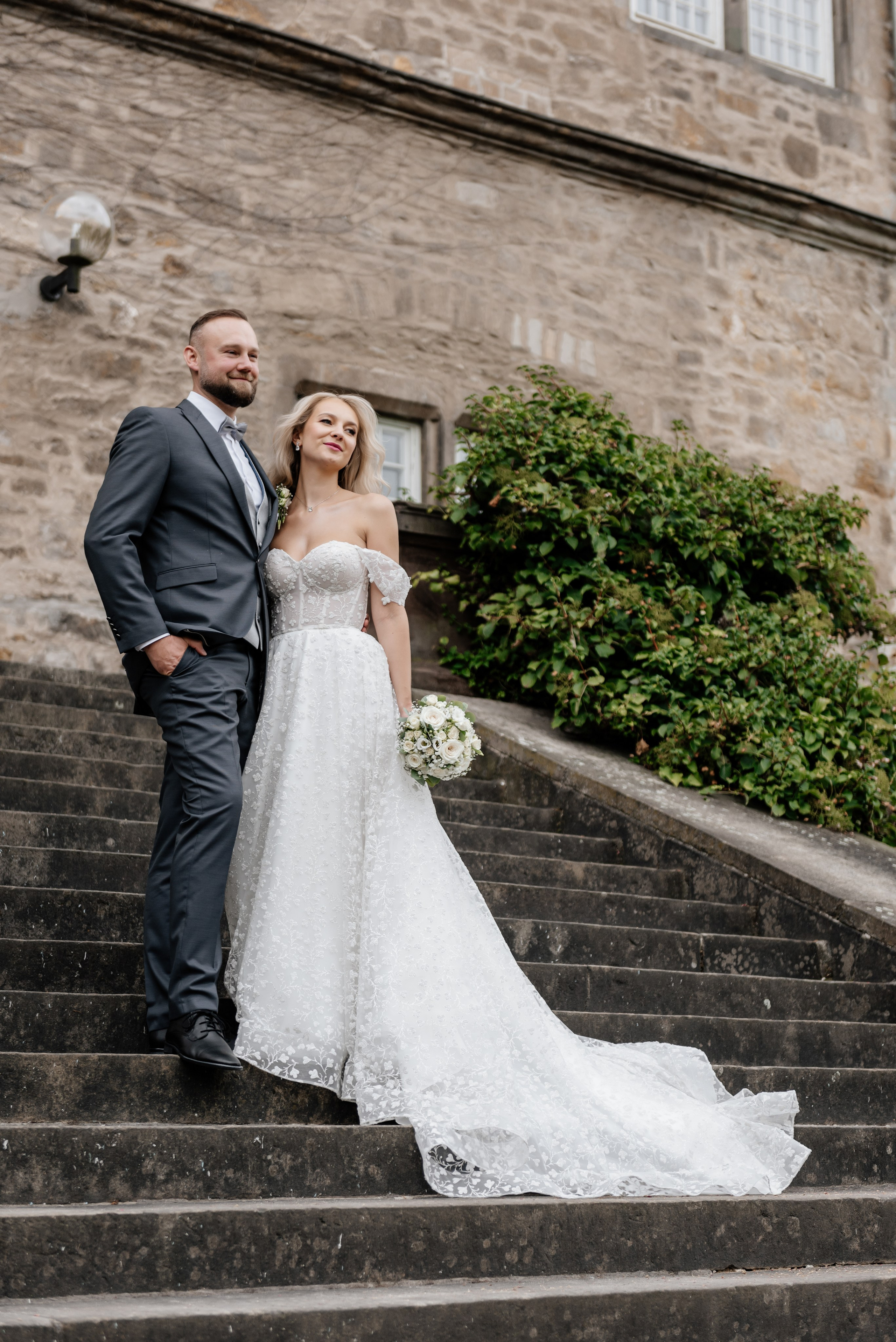 Hochzeitspaar im Freien vor Steinmauer – luxuriöser Hochzeitsfilm, Videograf in Bayern, Deutschland