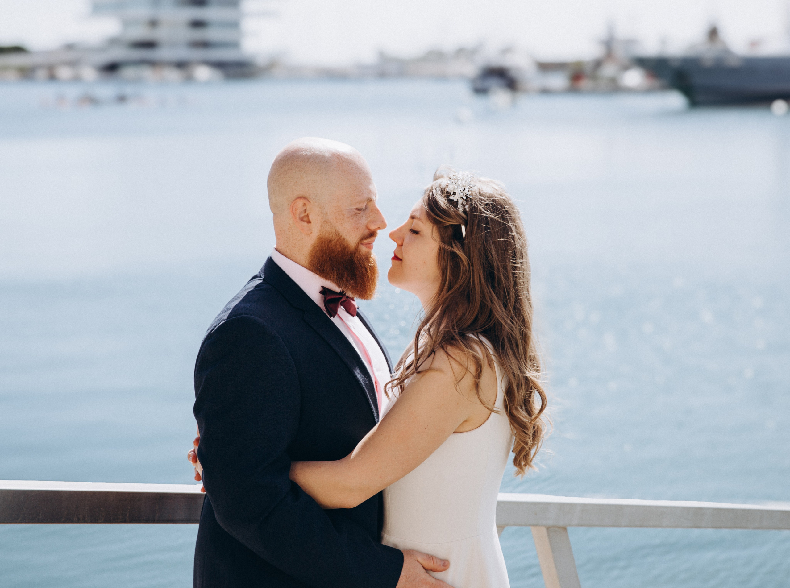 Intimate wedding moment in Valencia, Spain — close-up of a bride and groom gazing into each other’s eyes on a marina boardwalk, with soft sunlight and water in the background. Ideal for couples seeking romantic and natural wedding photography in Valencia and coastal Spain.