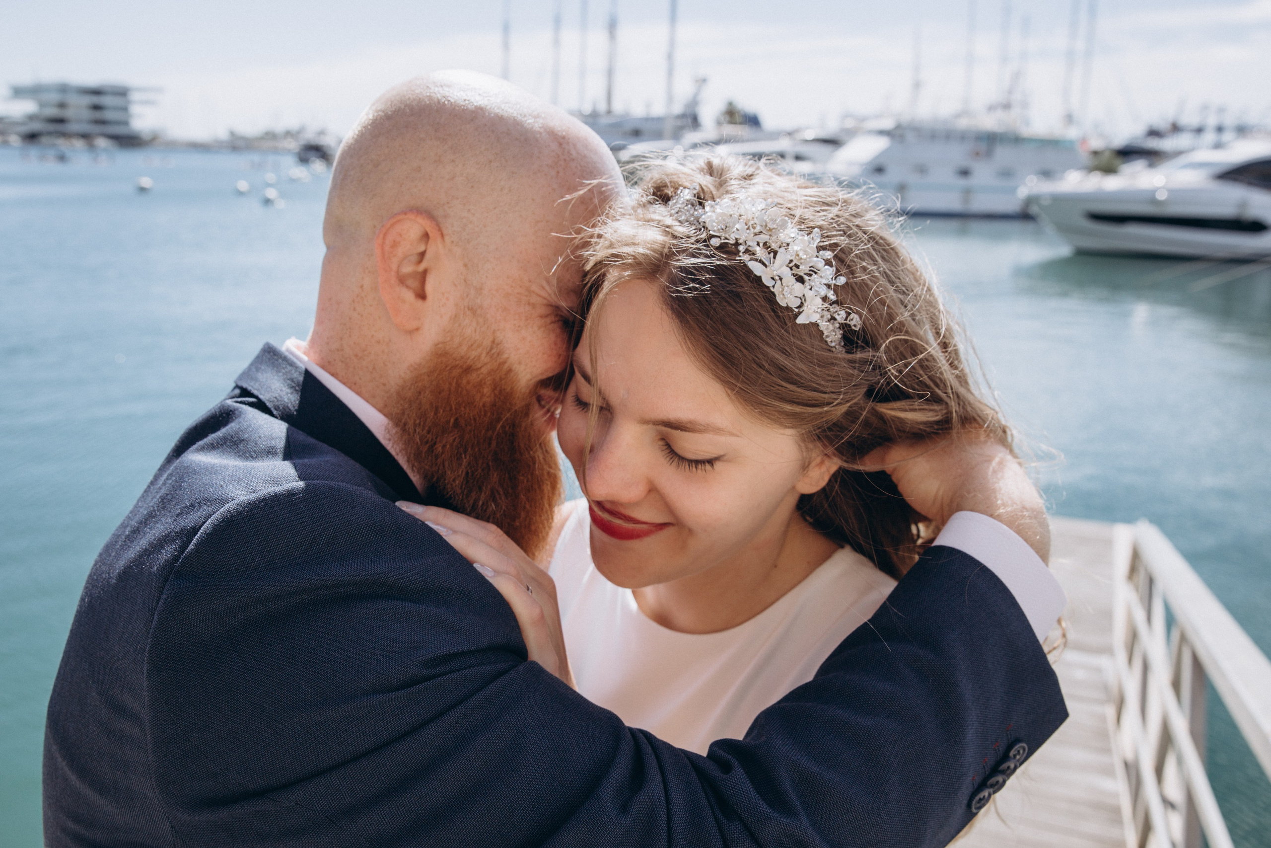 Emotional wedding moment in Valencia, Spain — intimate close-up of a groom gently embracing his smiling bride by the marina, with yachts in the background. Ideal for couples seeking romantic and heartfelt wedding photoshoots in Valencia and along Spain’s Mediterranean coast.