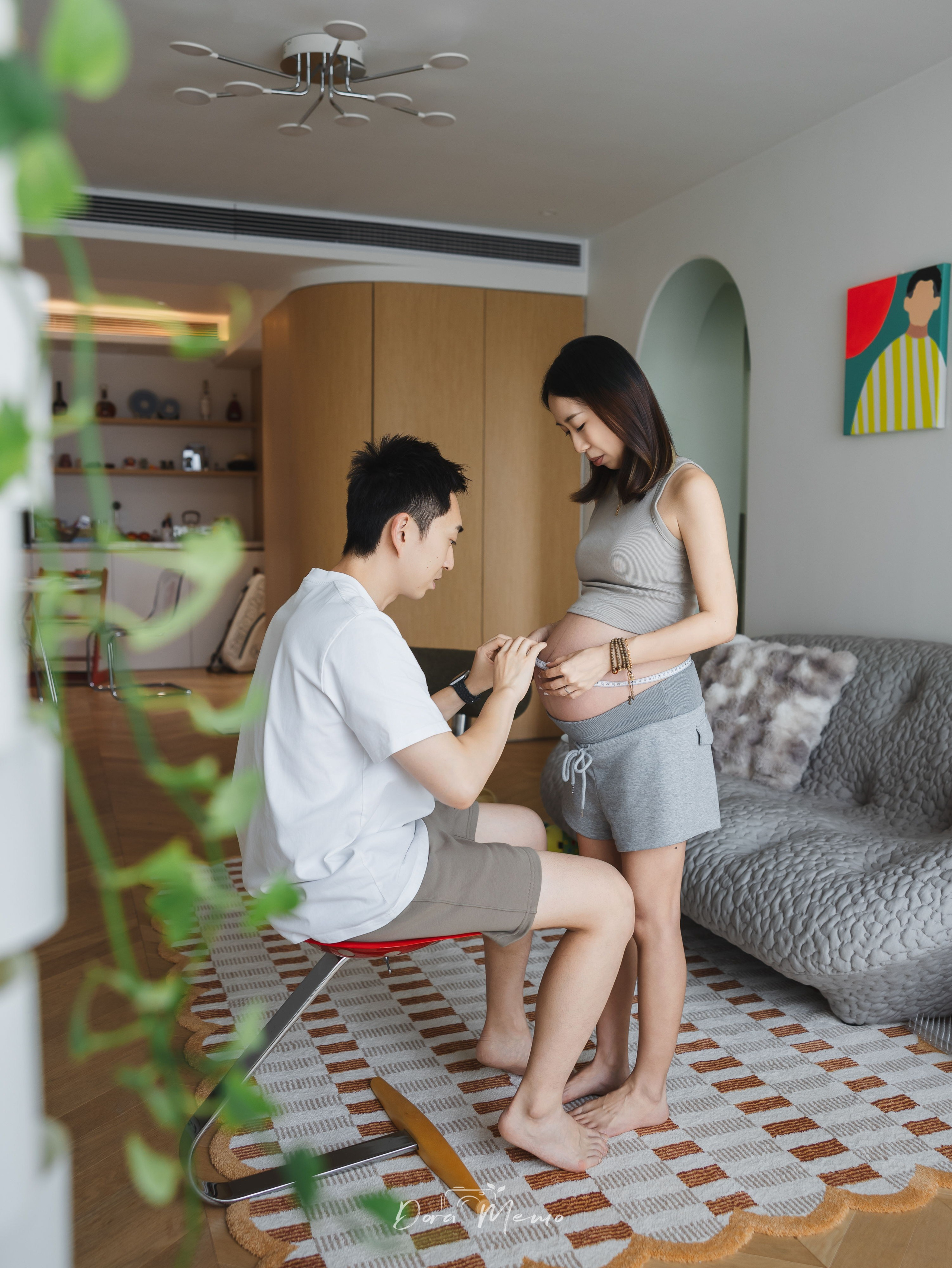 At-home maternity photo in Shanghai of an expectant father kissing the baby bump in a warm apartment.