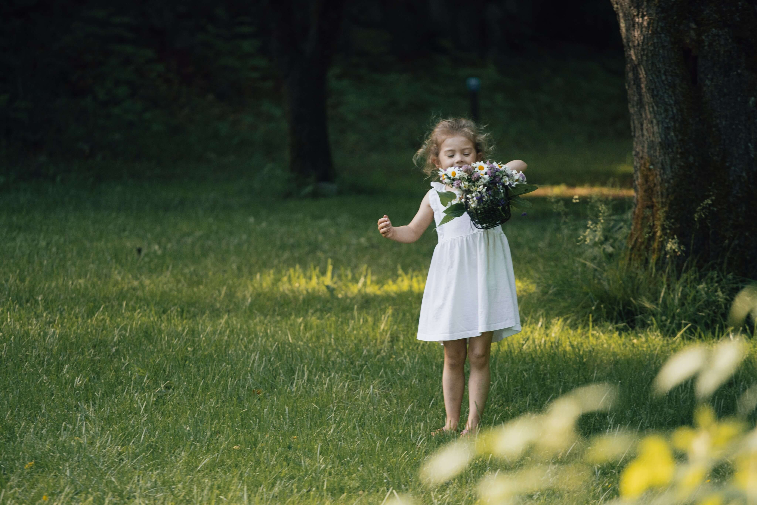 Barn plukker blomster i en grønn eng i Mule Varde