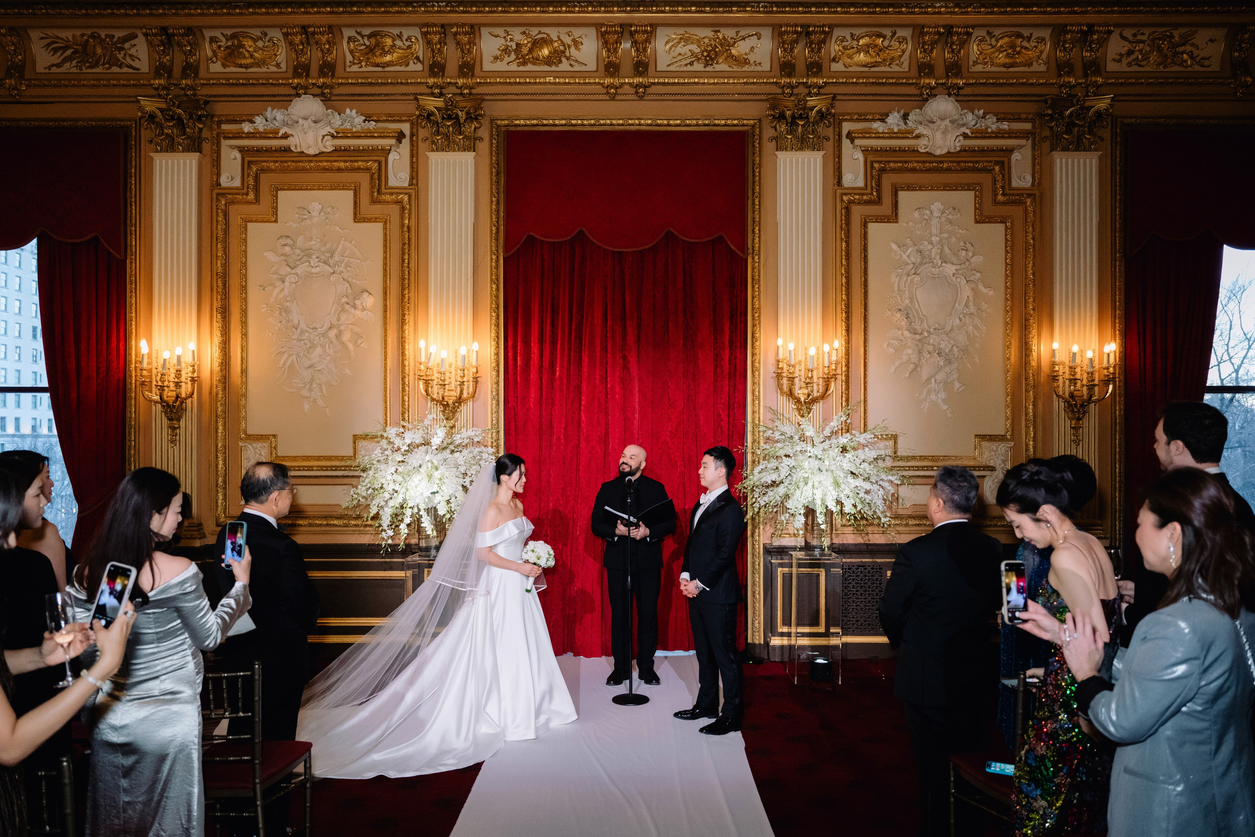 a bride and groom are standing in front of a red curtain