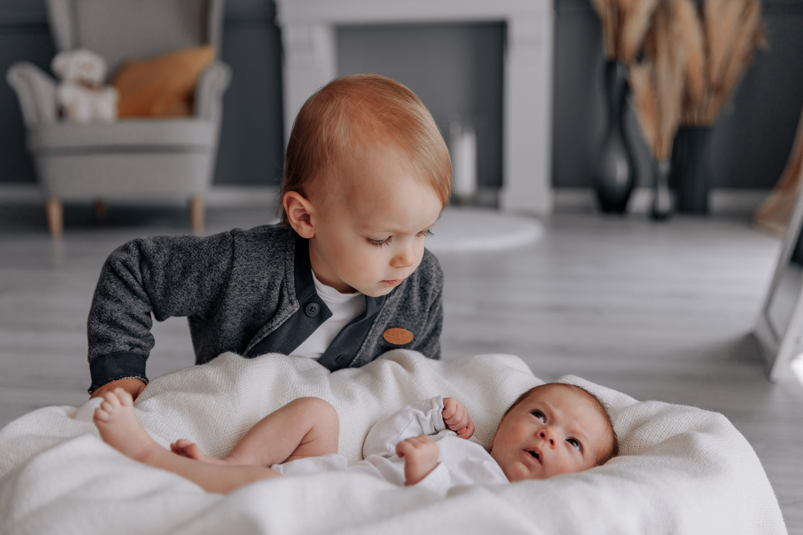 Älterer Bruder schaut auf seine Schwester, die liegt.