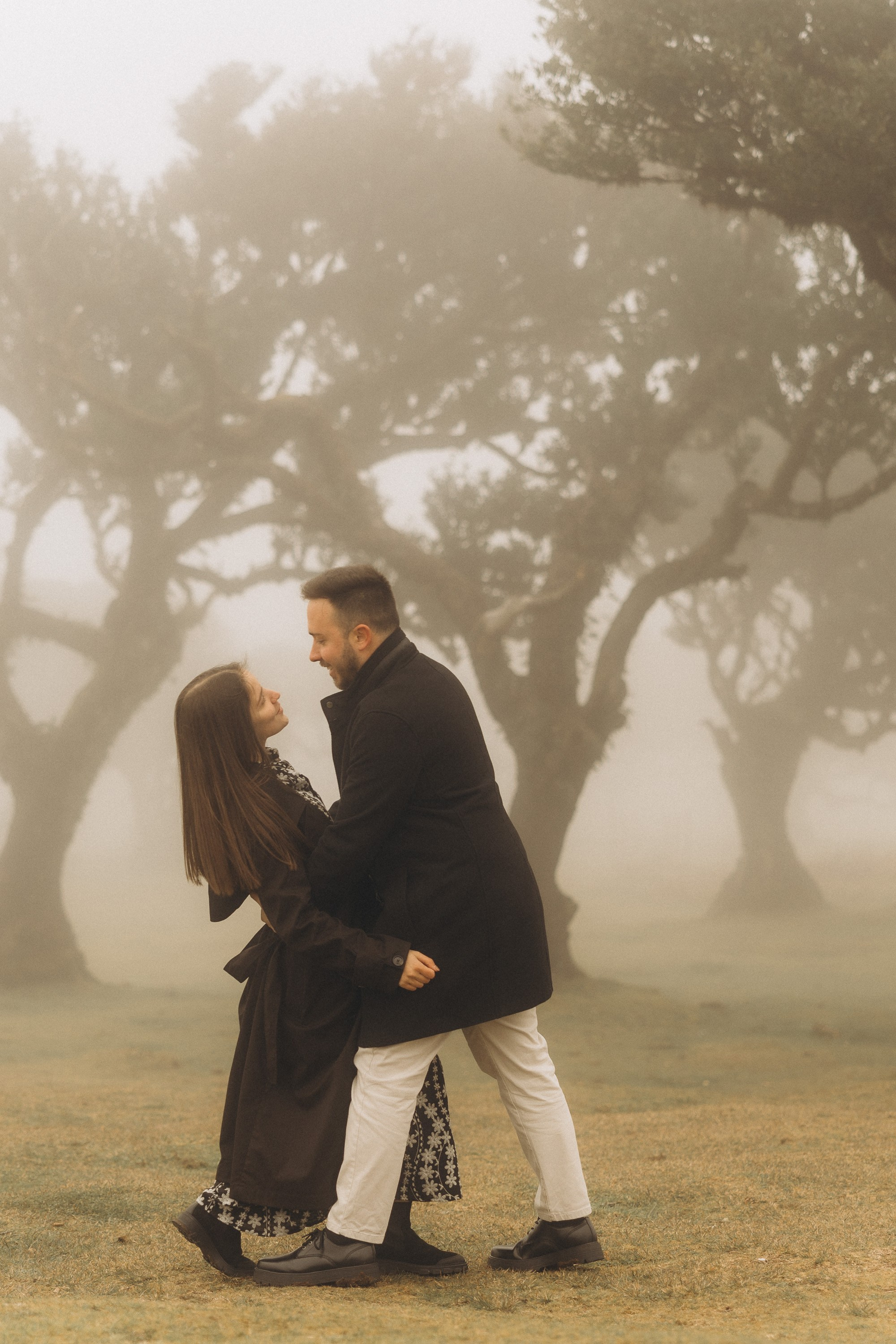 Couple photoshoot in Fanal Forest Madeira PortugalA romantic couple standing amidst the ancient laurel trees of Fanal Forest, Madeira, surrounded by a mystical fog that adds an ethereal touch to the scene