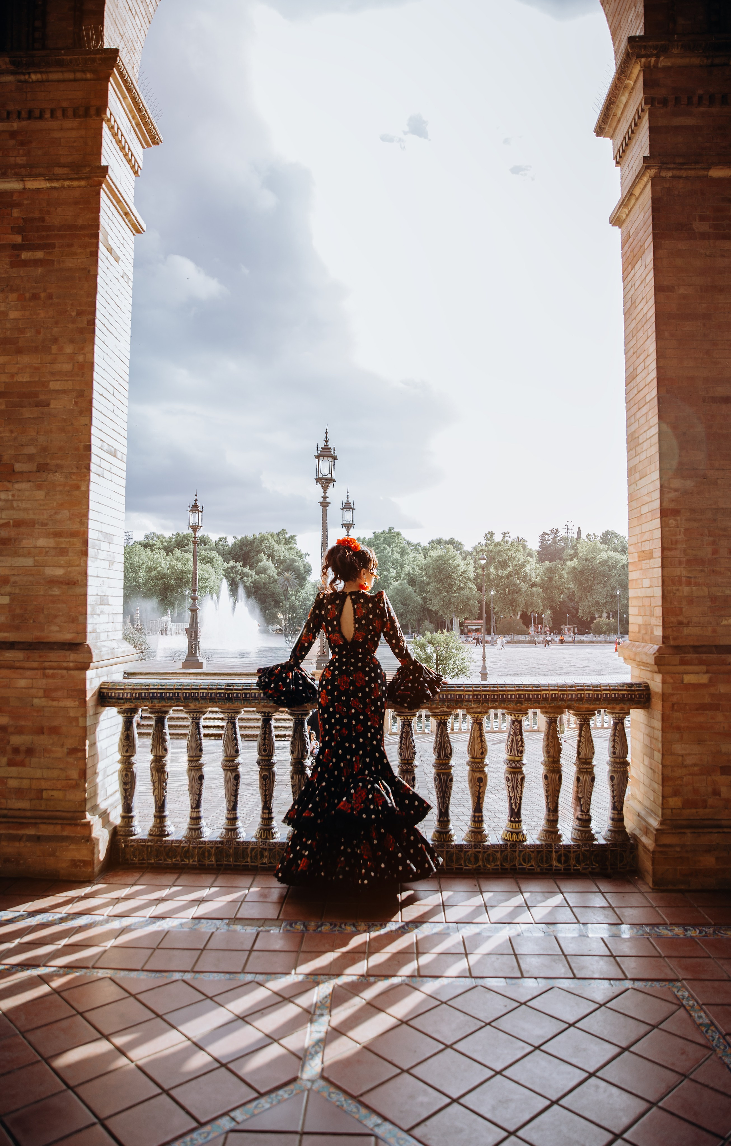 Драматичный портрет женщины в традиционном платье фламенко у фонтана на площади Испании в Севилье, Испания — идеальное вдохновение для культурных и элегантных портретных фотосессий в Севилье и Андалусии.