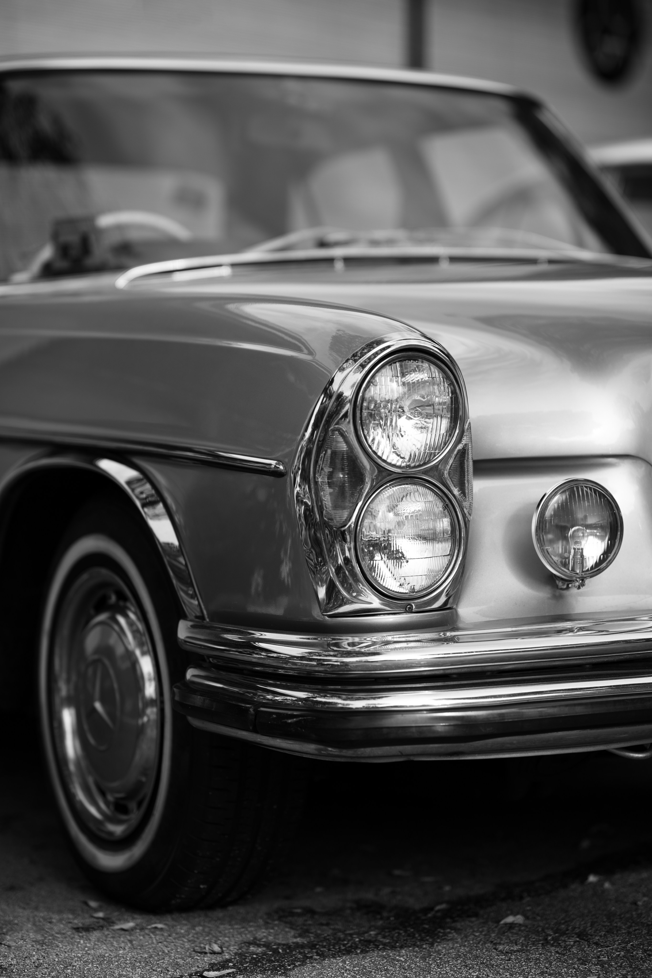 Mercedes-Benz W111 coupe headlamp cluster – refined monochrome capture of a vintage Mercedes coupe’s stacked headlights and chrome bumper, demonstrating heritage-car visual branding expertise in Singapore.