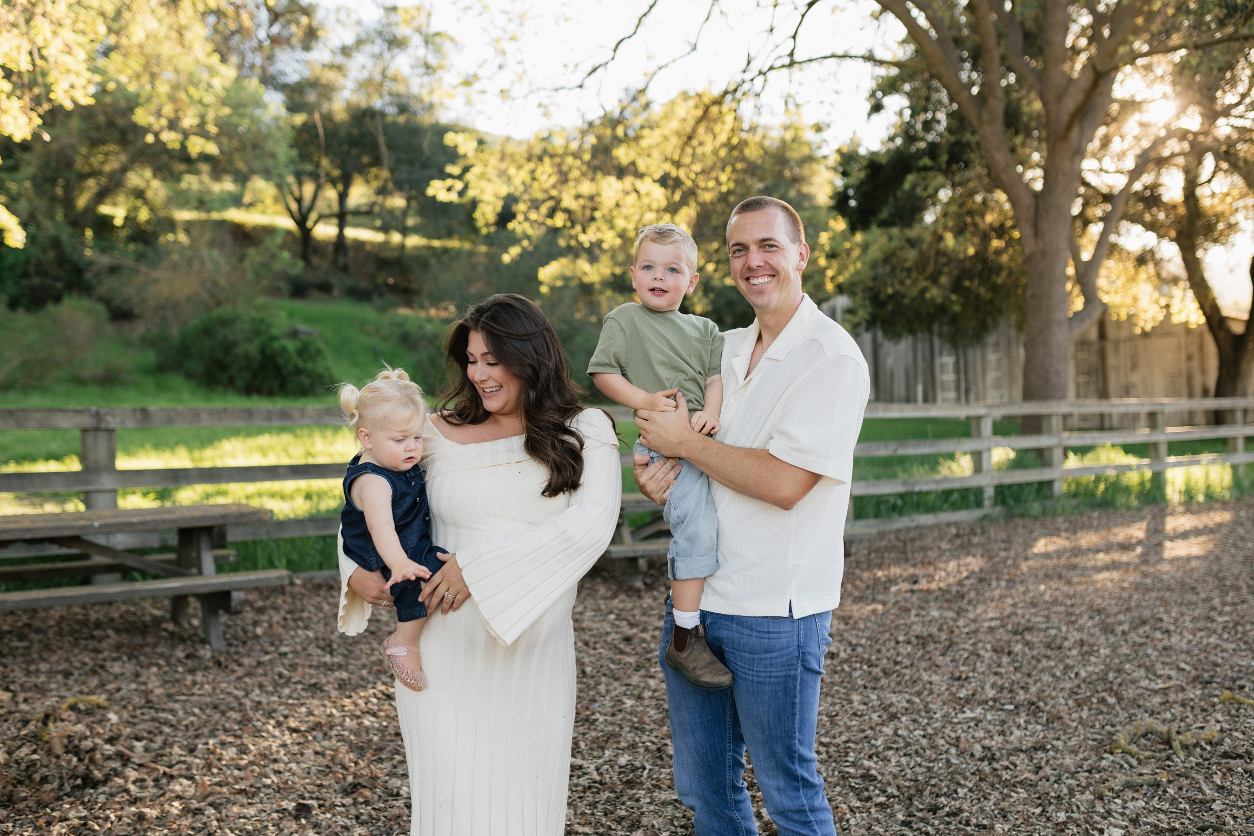 Family walking together through a green park during golden hour maternity lifestyle photoshoot in the Bay Area