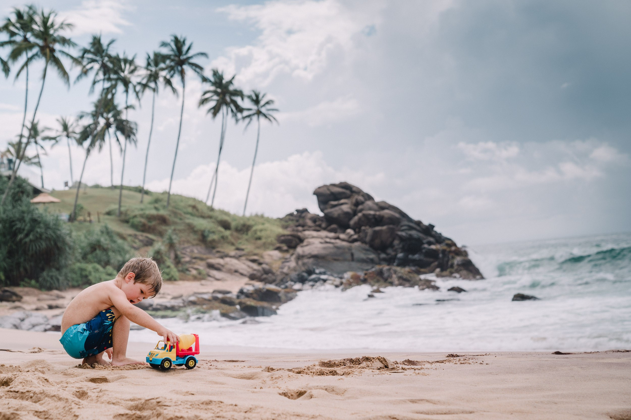 Landscape of the huge rocks and palm trees and dramatic ocean and boy playing 