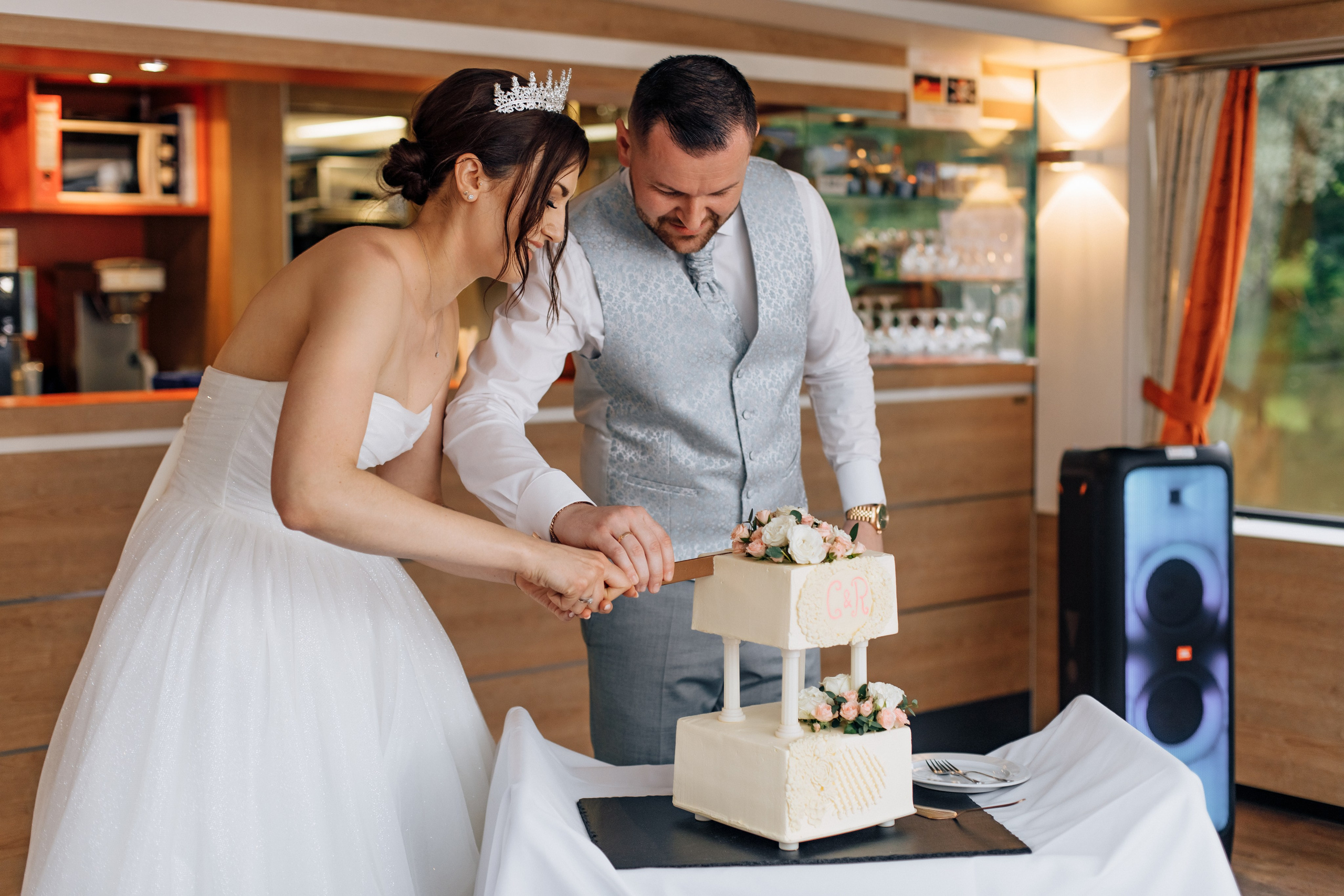 Der Bräutigam und die Braut schneiden gemeinsam die Hochzeitstorte an.