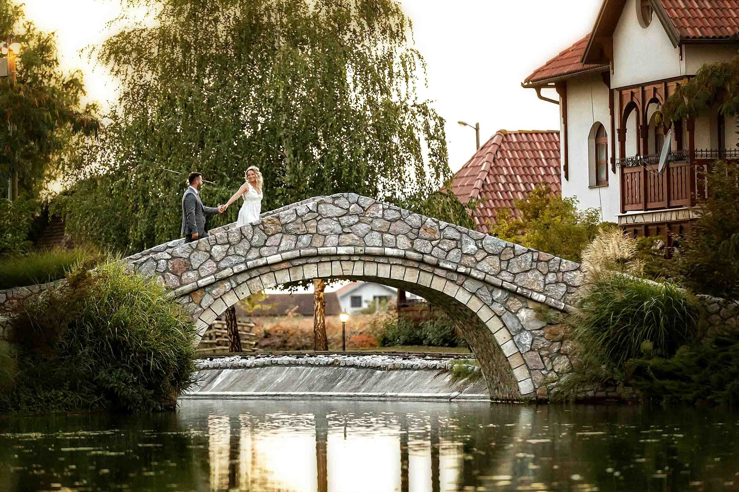 Mladenci prelaze bajkoviti kameniti most iznad reke