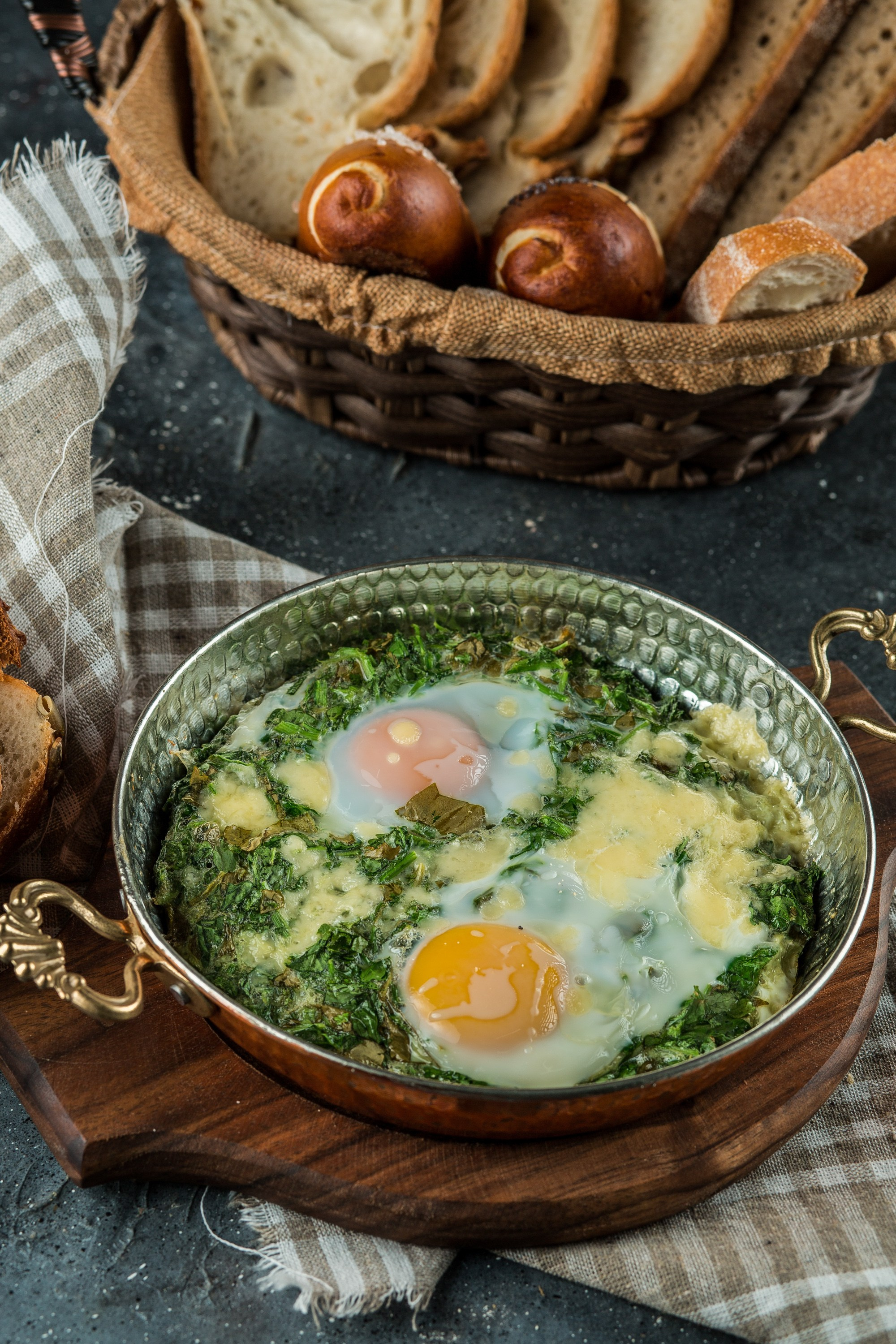 Göyərti və pendirli iki yumurtalı qayğanaq, səbətdə müxtəlif çörəklərlə.