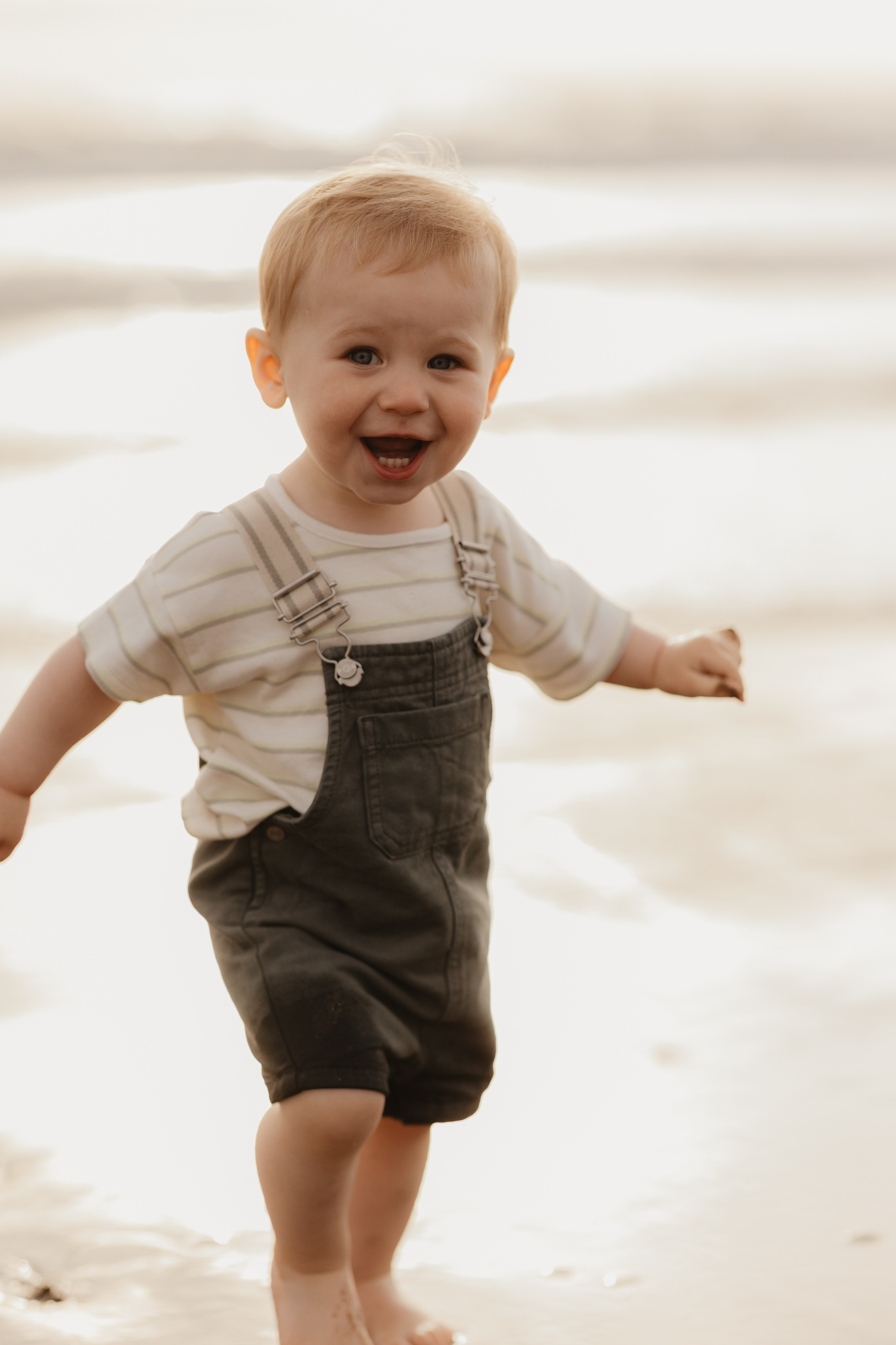 Enfant riant face à l’océan, lumière dorée de fin de journée, photographie lifestyle