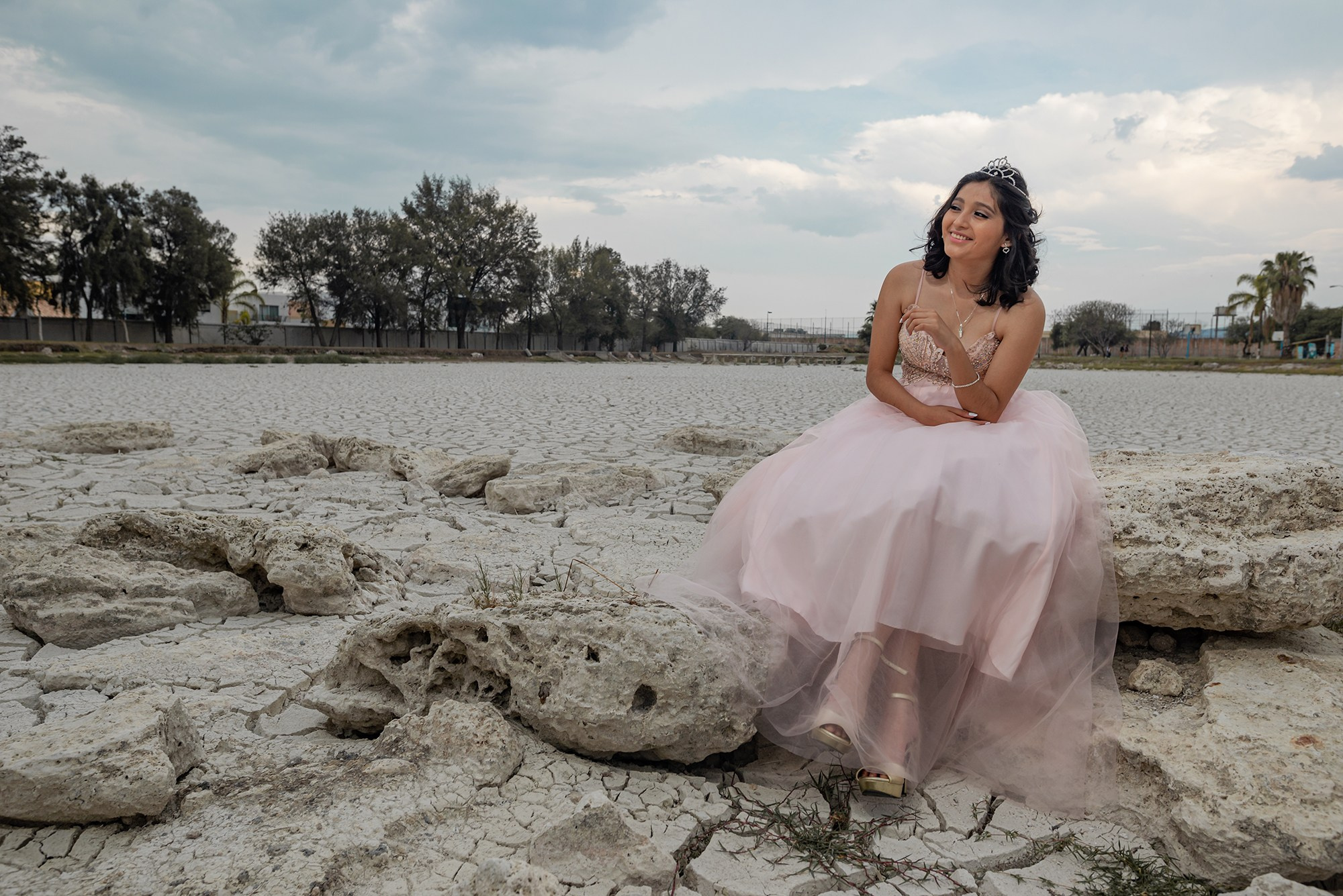 Creative fashion-inspired photoshoot in Baja California Sur – Michelle wearing a pink quinceañera-style dress in a desert landscape with cracked ground, artistic photography in Los Cabos