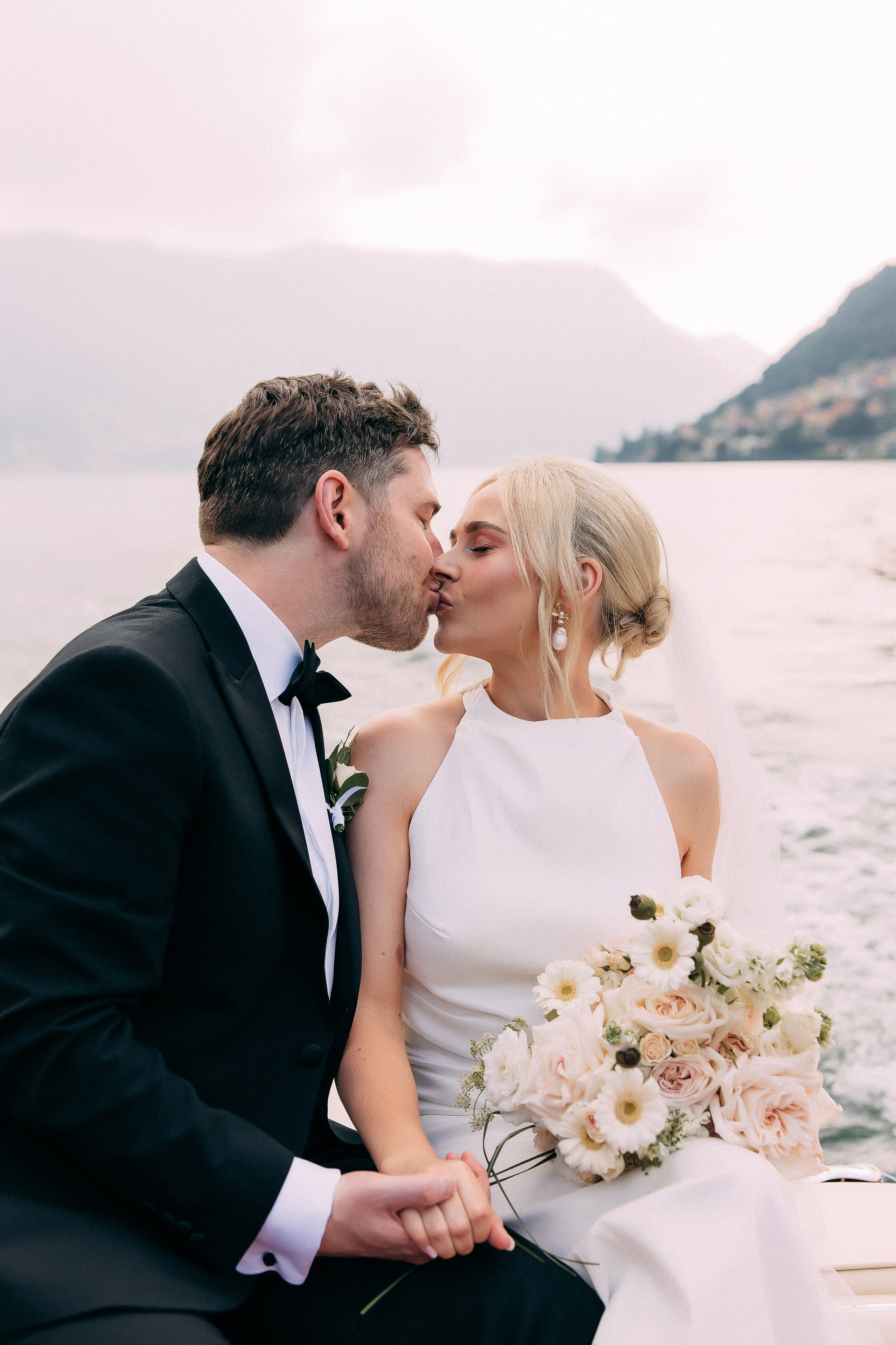 Bride and groom sitting on the boat with Lake Como views at Villa Lario, Italy