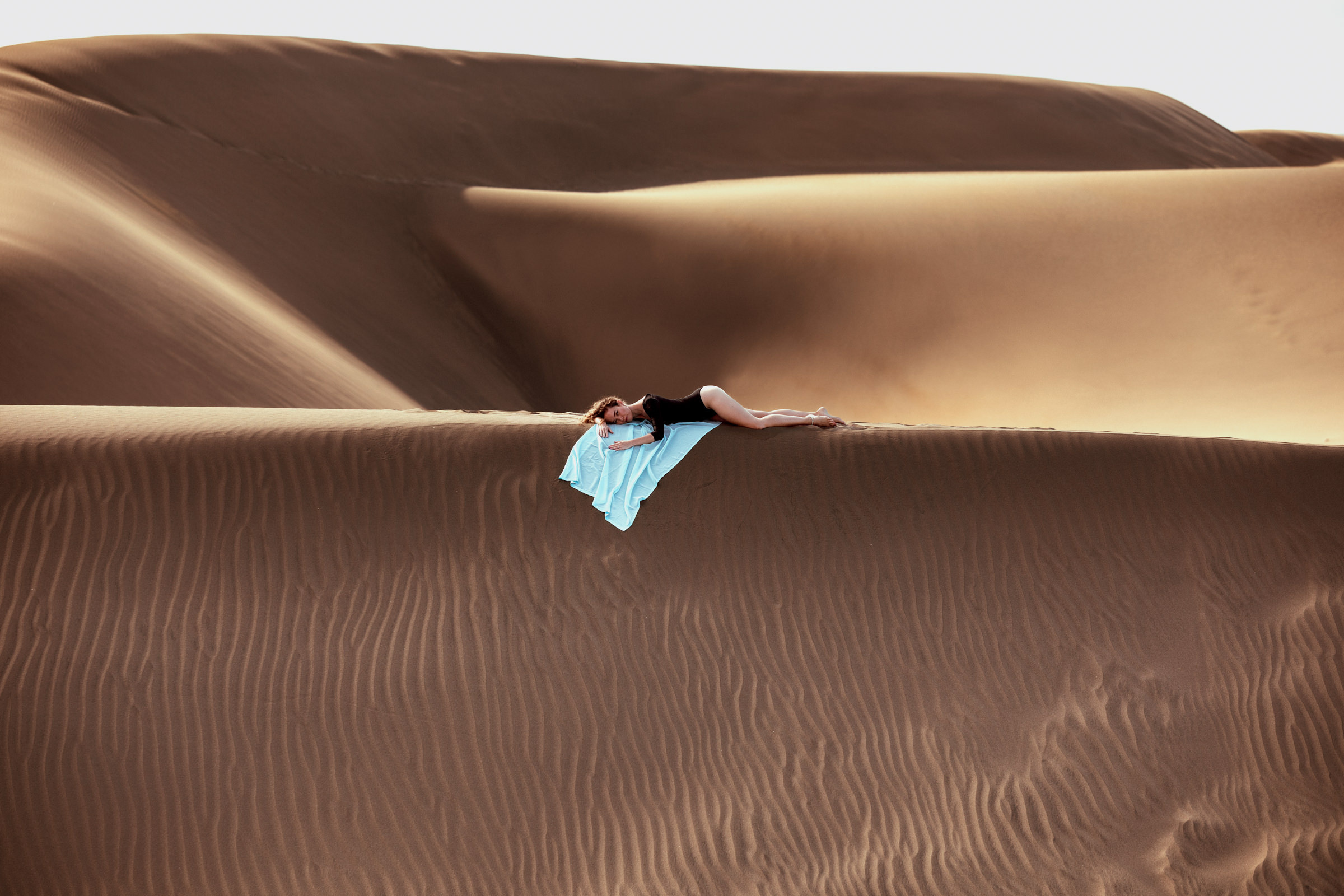 Photo Shoot Desert Maspalomas A person laying on top of a sand dune.