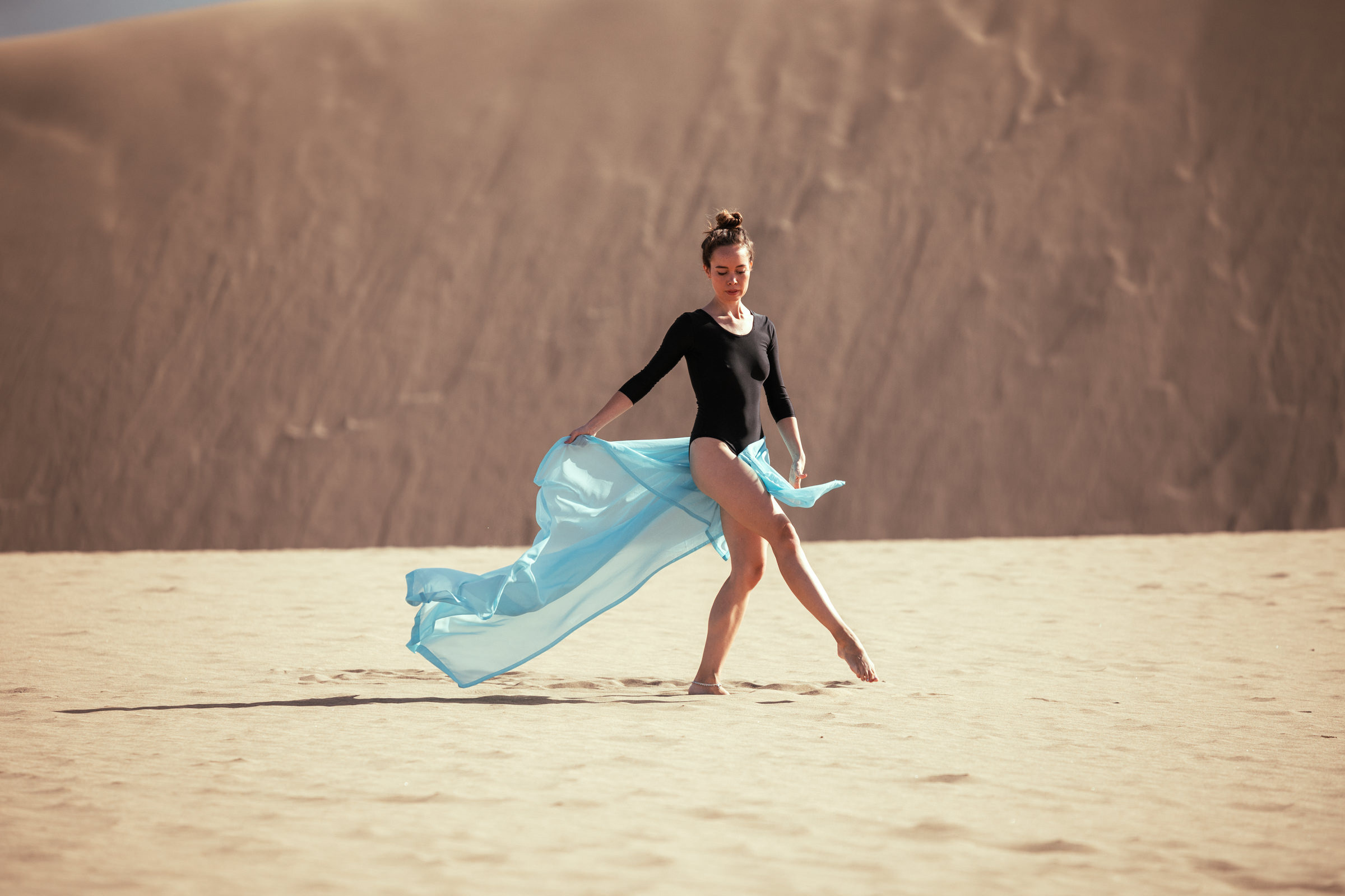 A woman in a blue dress is dancing in the sand. Nice Desert Maspalomas Walking
