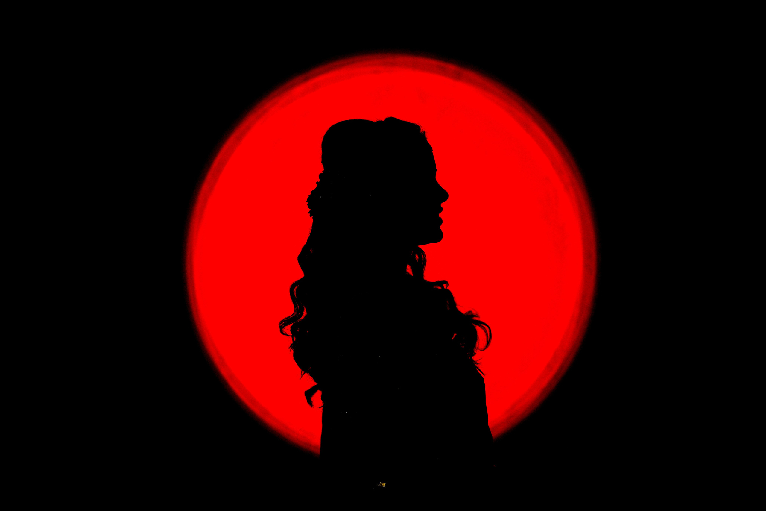 dramatic studio silhouette portrait of a woman's profile against a bright red circle background in Malleshwaram, Bengaluru