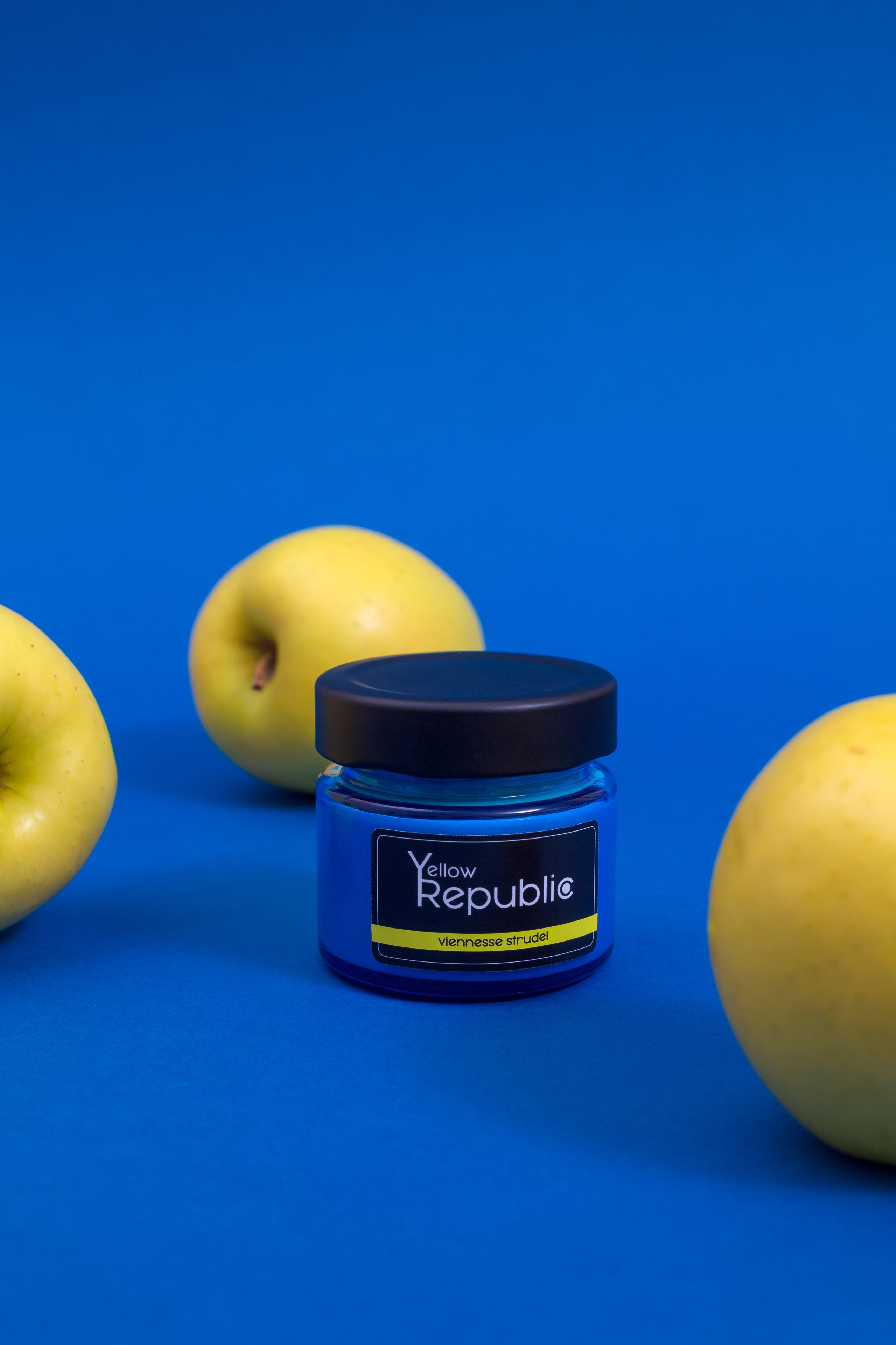 vela en un frasco sobre un fondo azul con manzanas