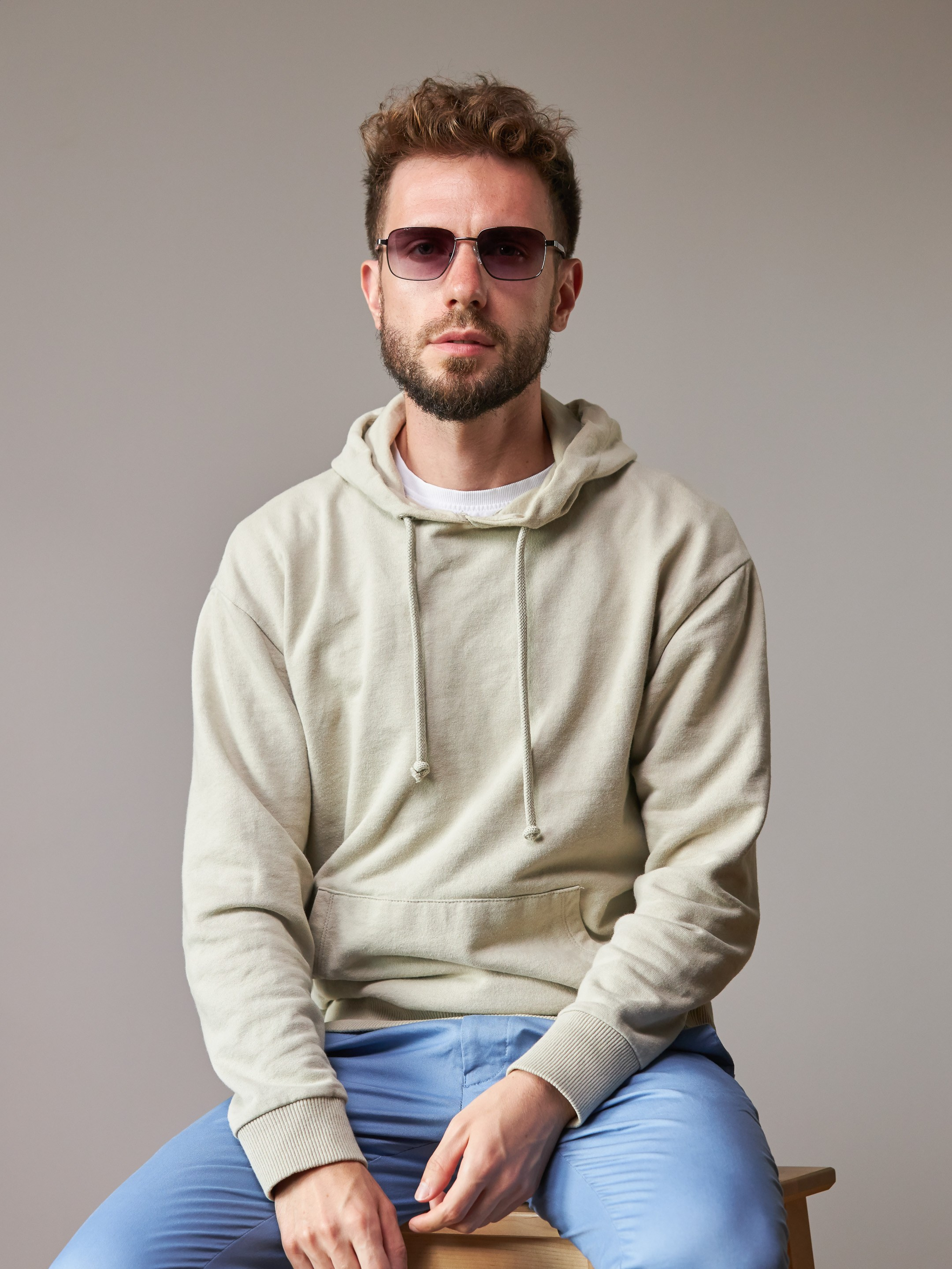 Eyewear model photoshoot - studio portrait of a young man on warm grey background - photographer Andrey Dunin