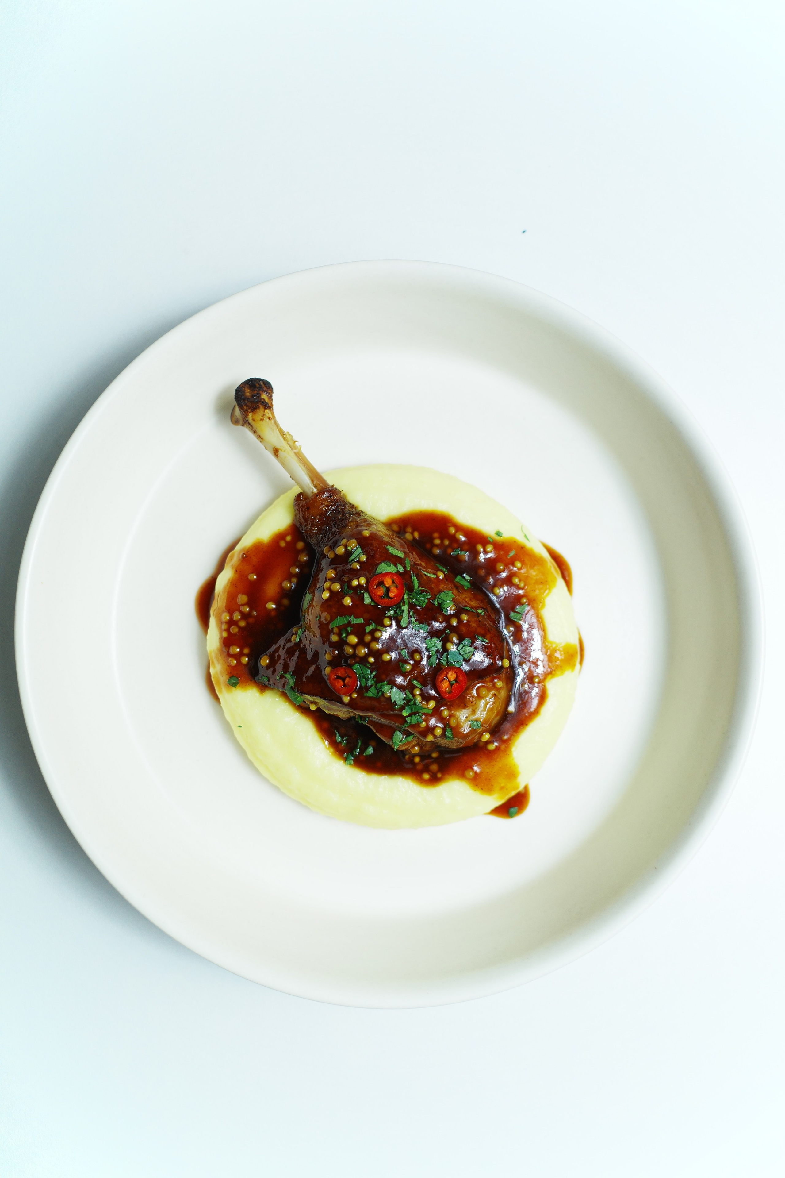 Farm-raised duck leg confit with creamy potato purée and demi-glace sauce with whole-grain mustard.