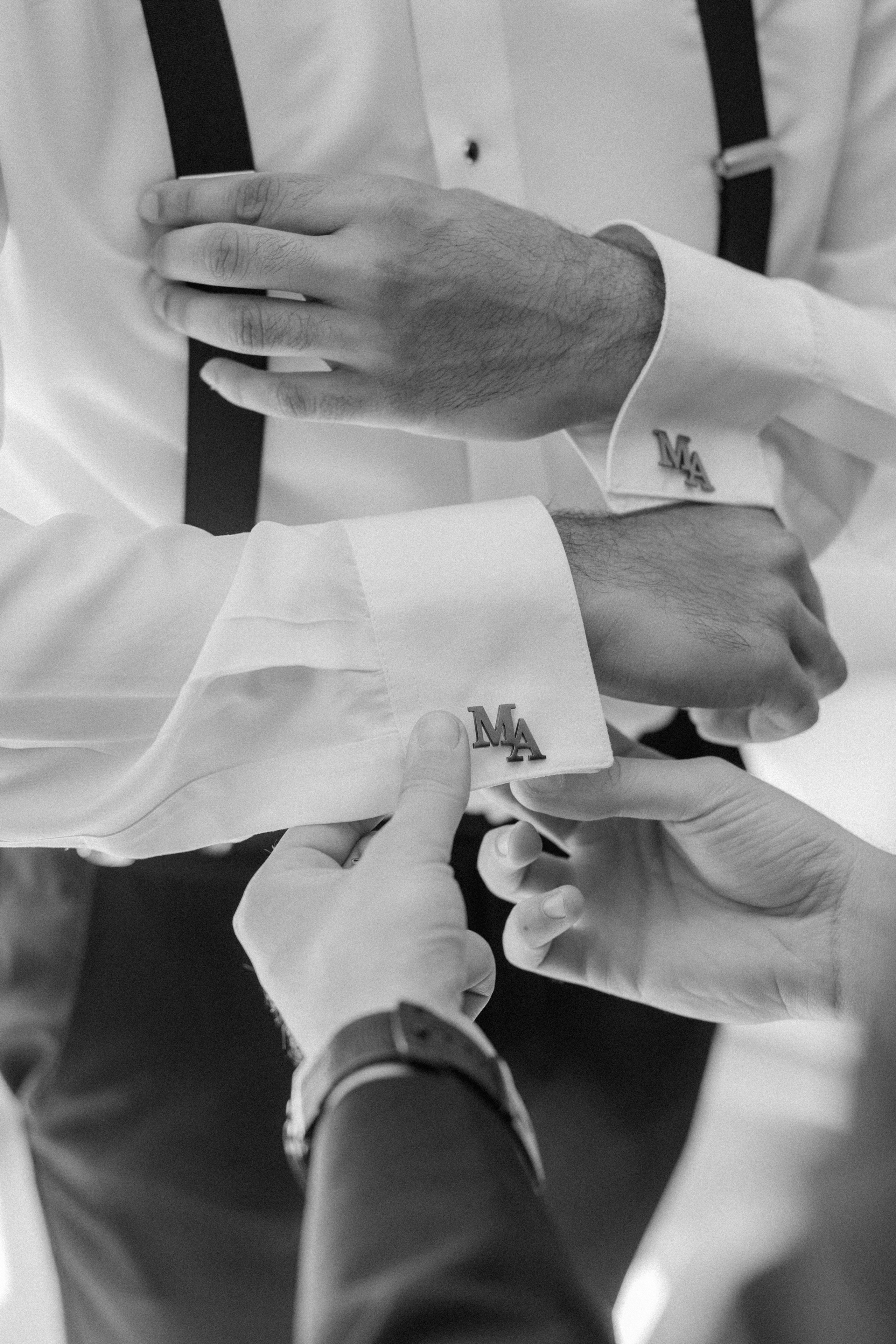 Bride helping groom with jacket during morning preparations