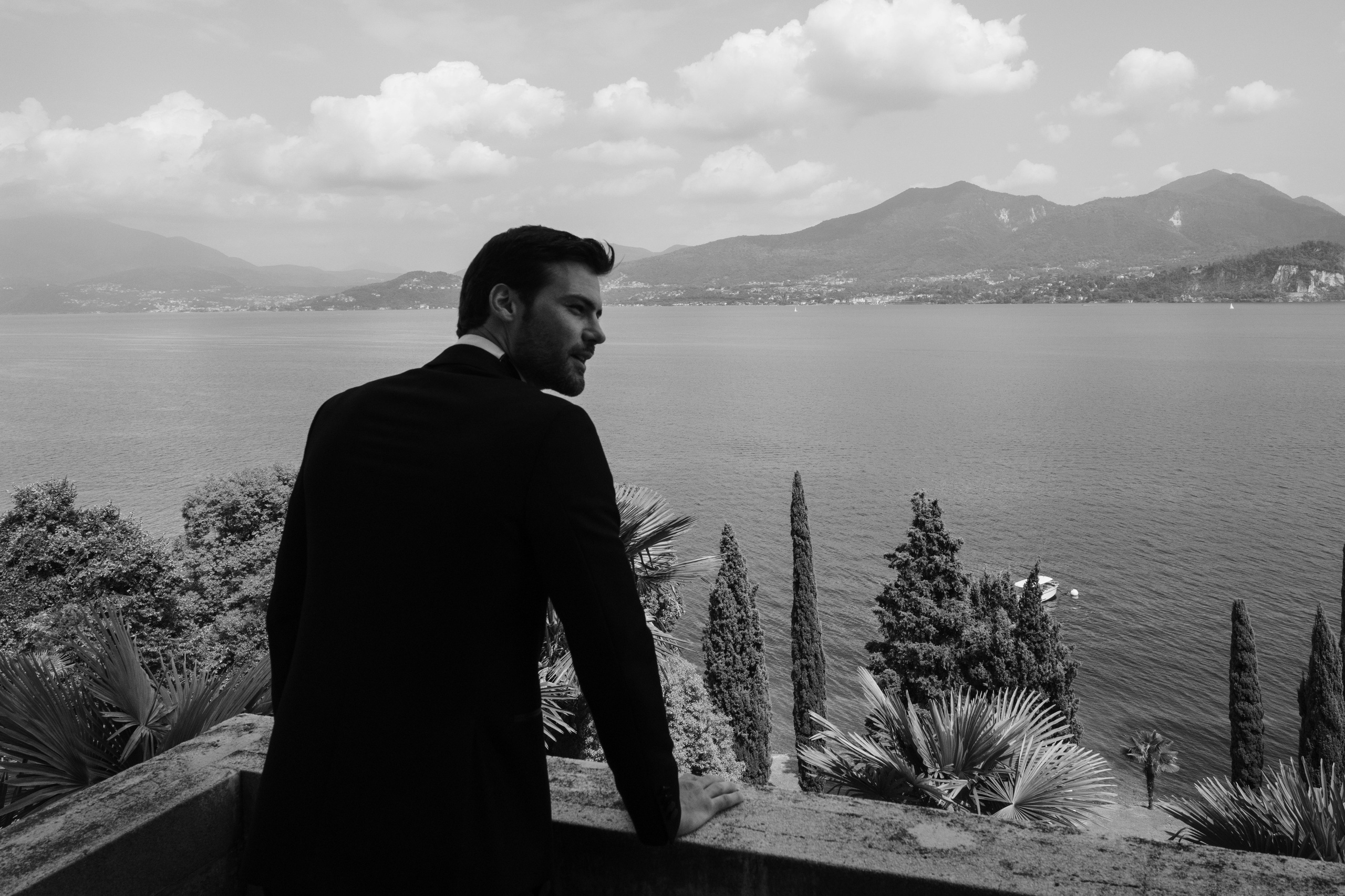 a man in a suit looking out over a lake