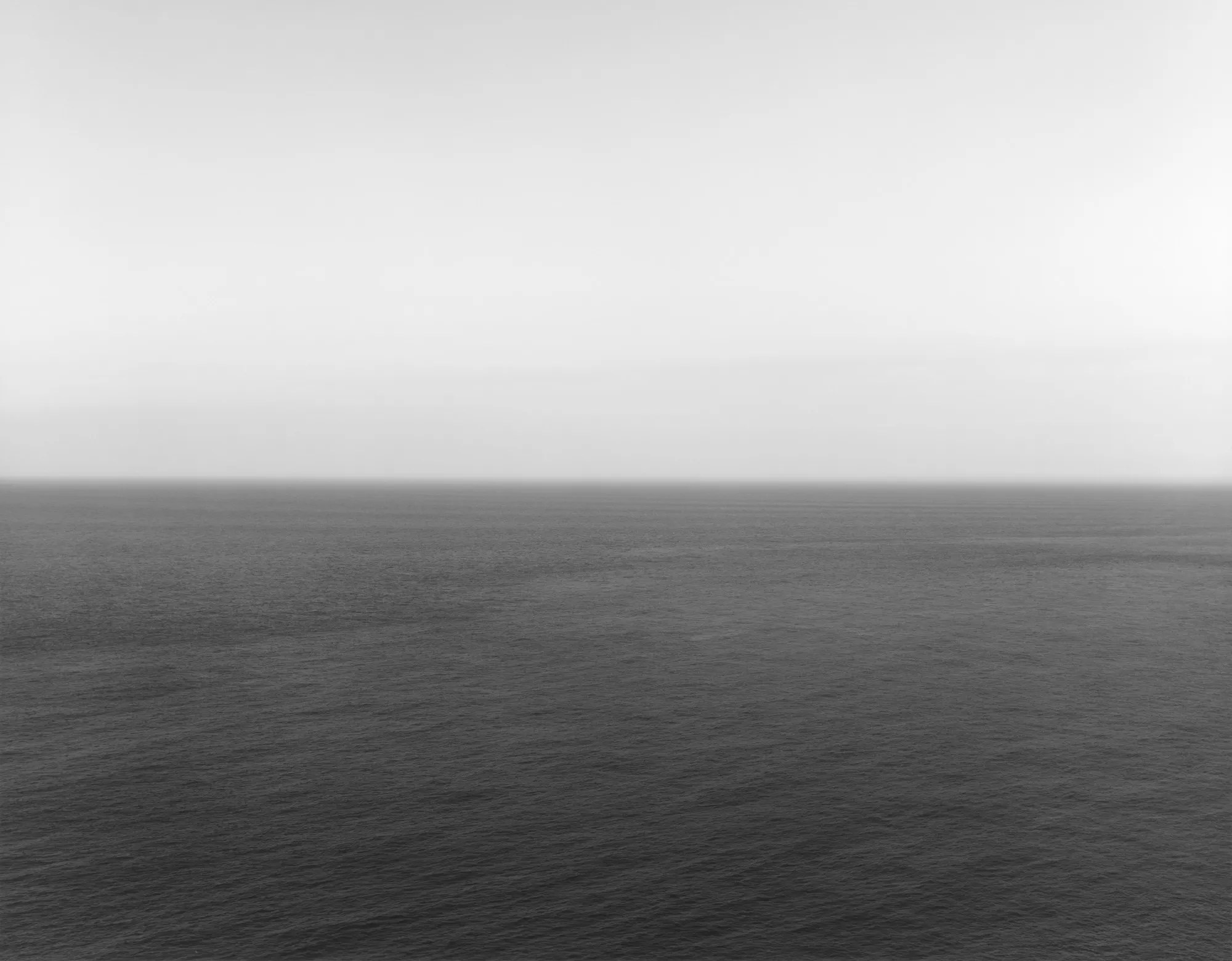 Длительные экспозиции стирают движение: море превращается в ровную горизонталь, а целый фильм — в один ослепительно белый кадр. Время исчезает в длительности.