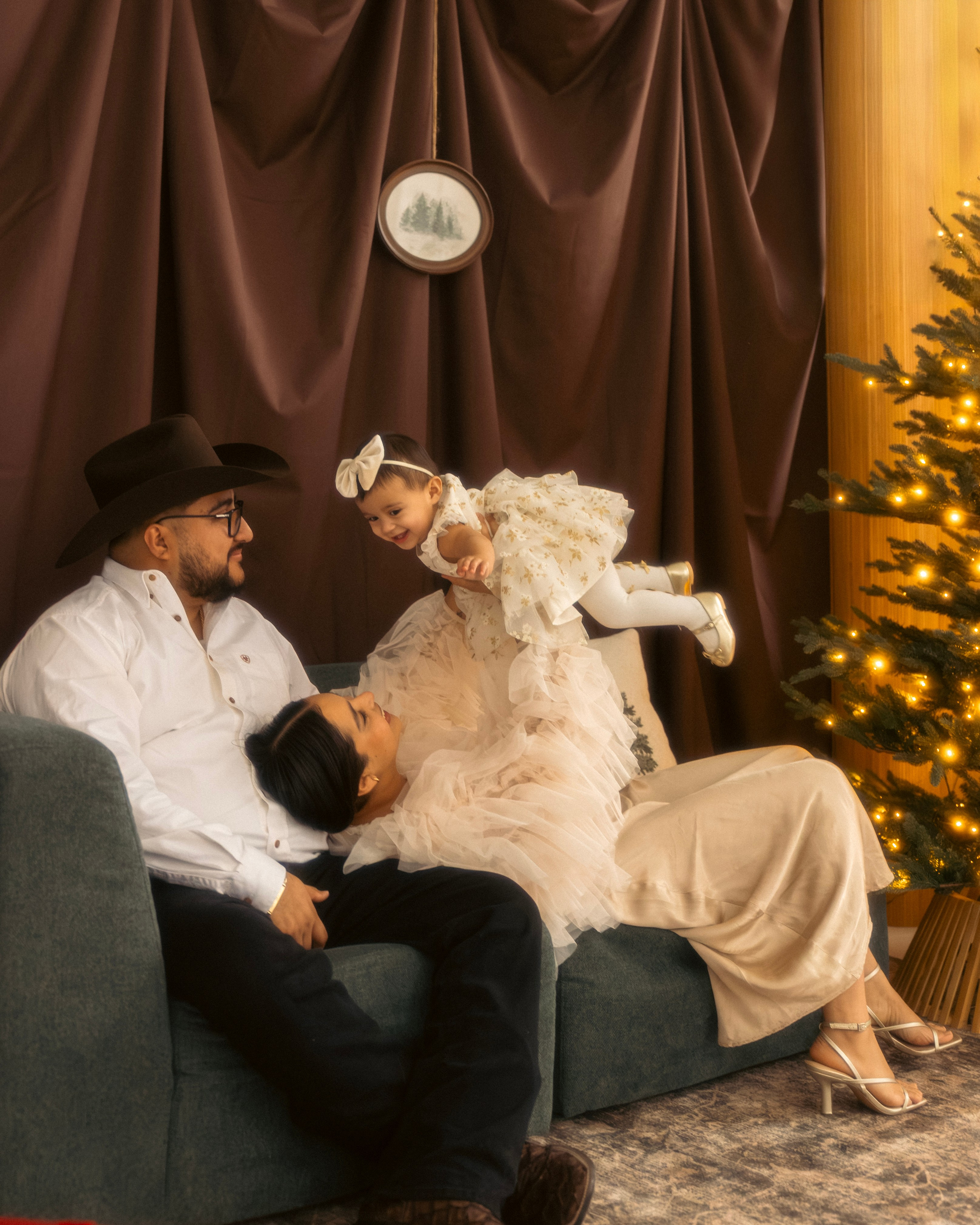 Mother cuddling her baby on a sofa during a cozy Christmas photo session