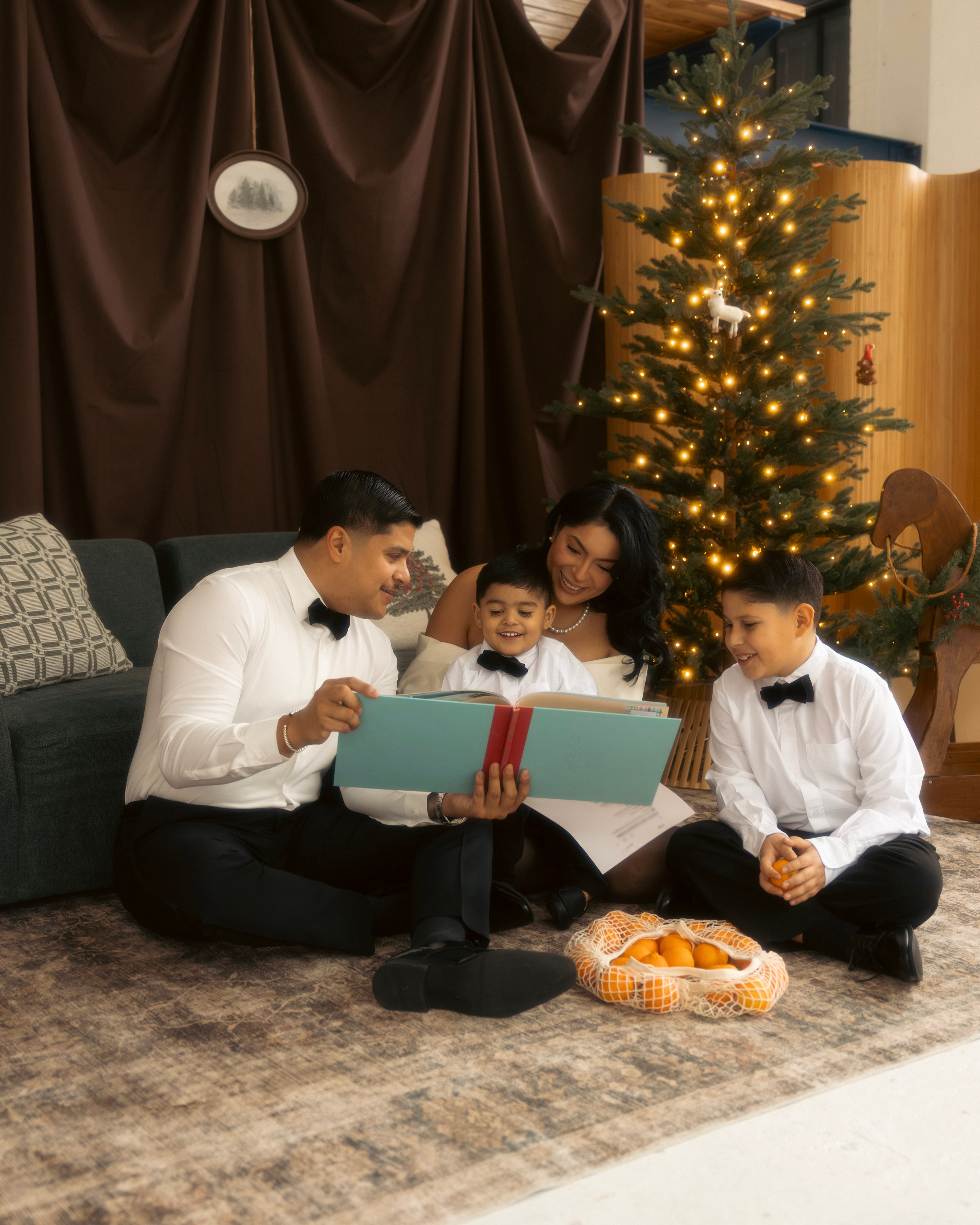 Family cuddling together by the Christmas tree during a cozy holiday photo session