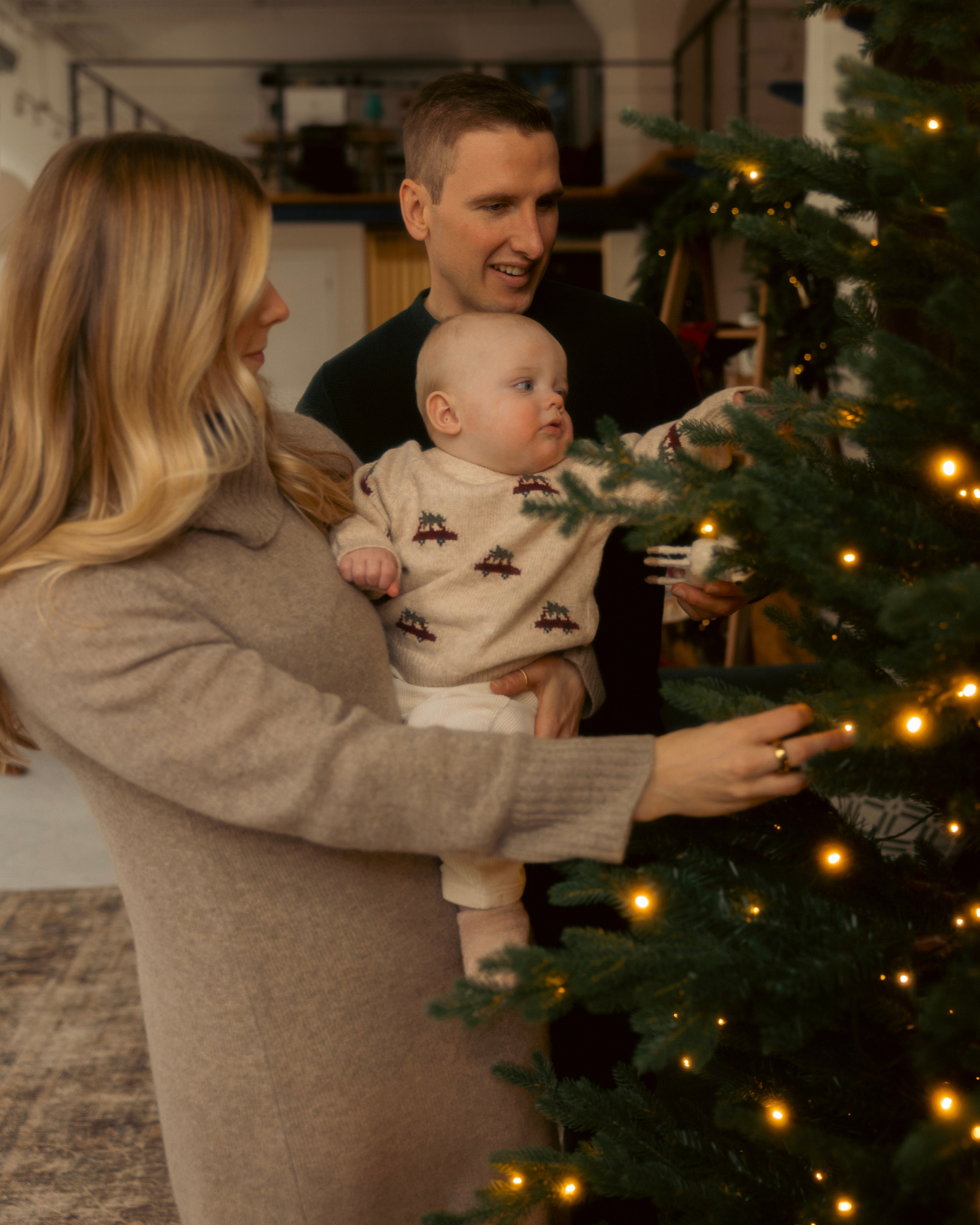 Mother holding her baby by the Christmas tree during a cozy Chicago holiday session