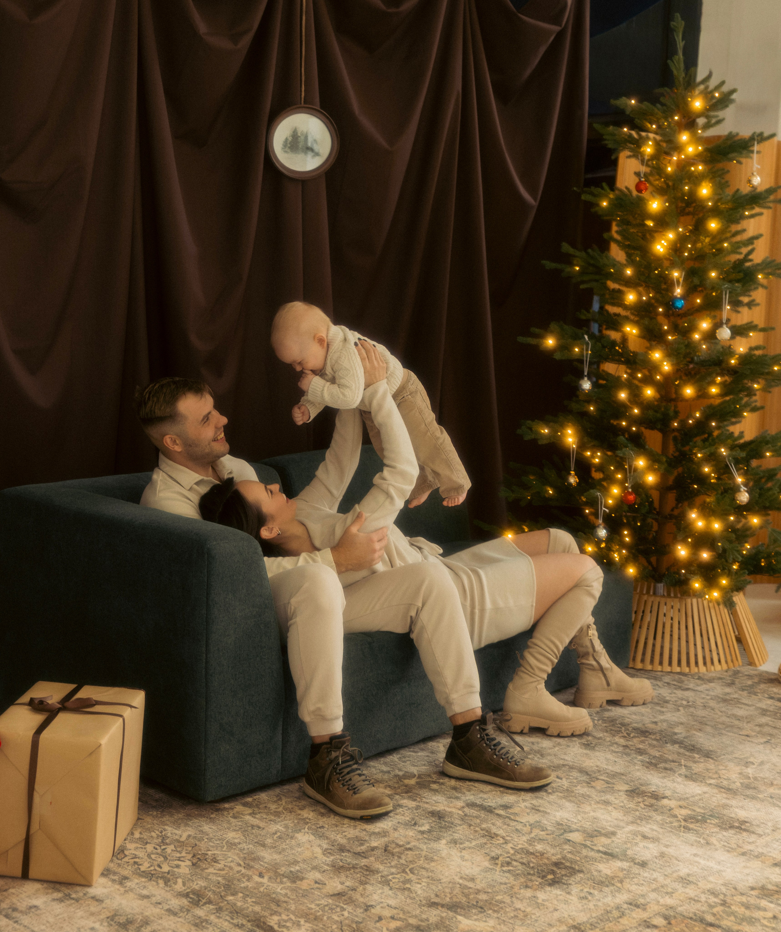 Mother and child sharing a playful moment by the Christmas tree during a holiday photo session