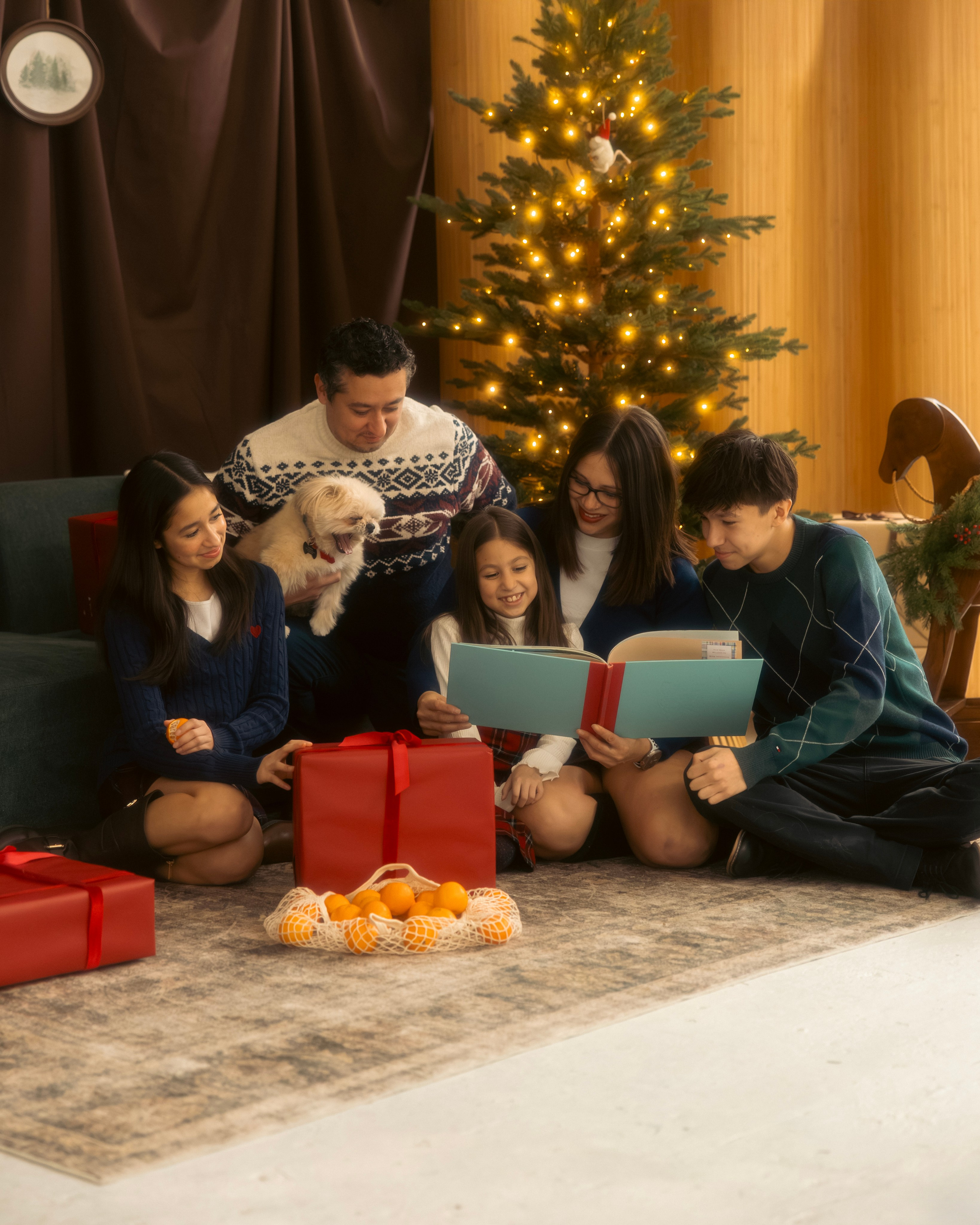 Whole family and their dog near Christmas tree in warm Christmas photoshoot